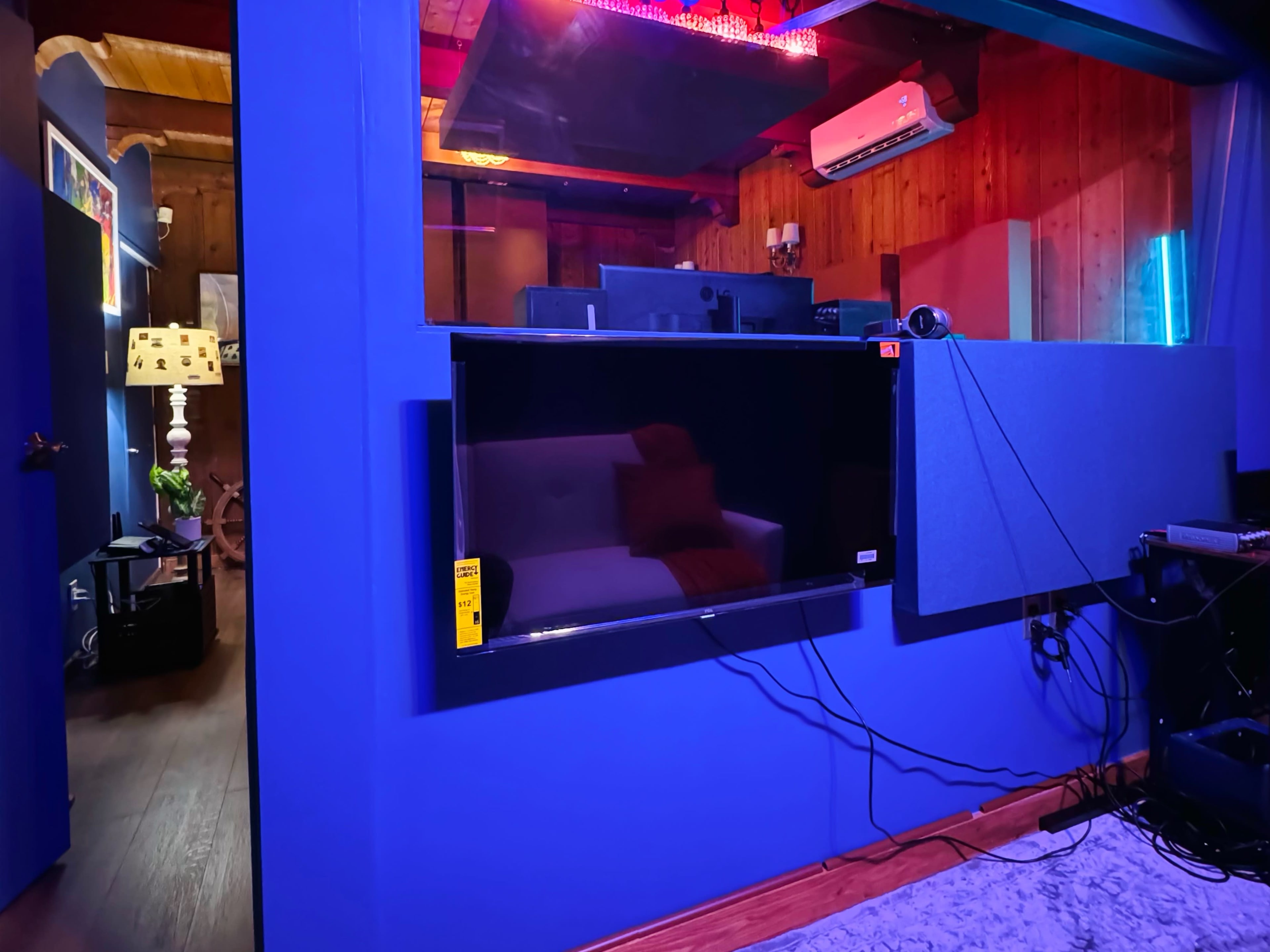 A room with blue walls featuring a mounted television, a soundproof panel, and warm lighting.