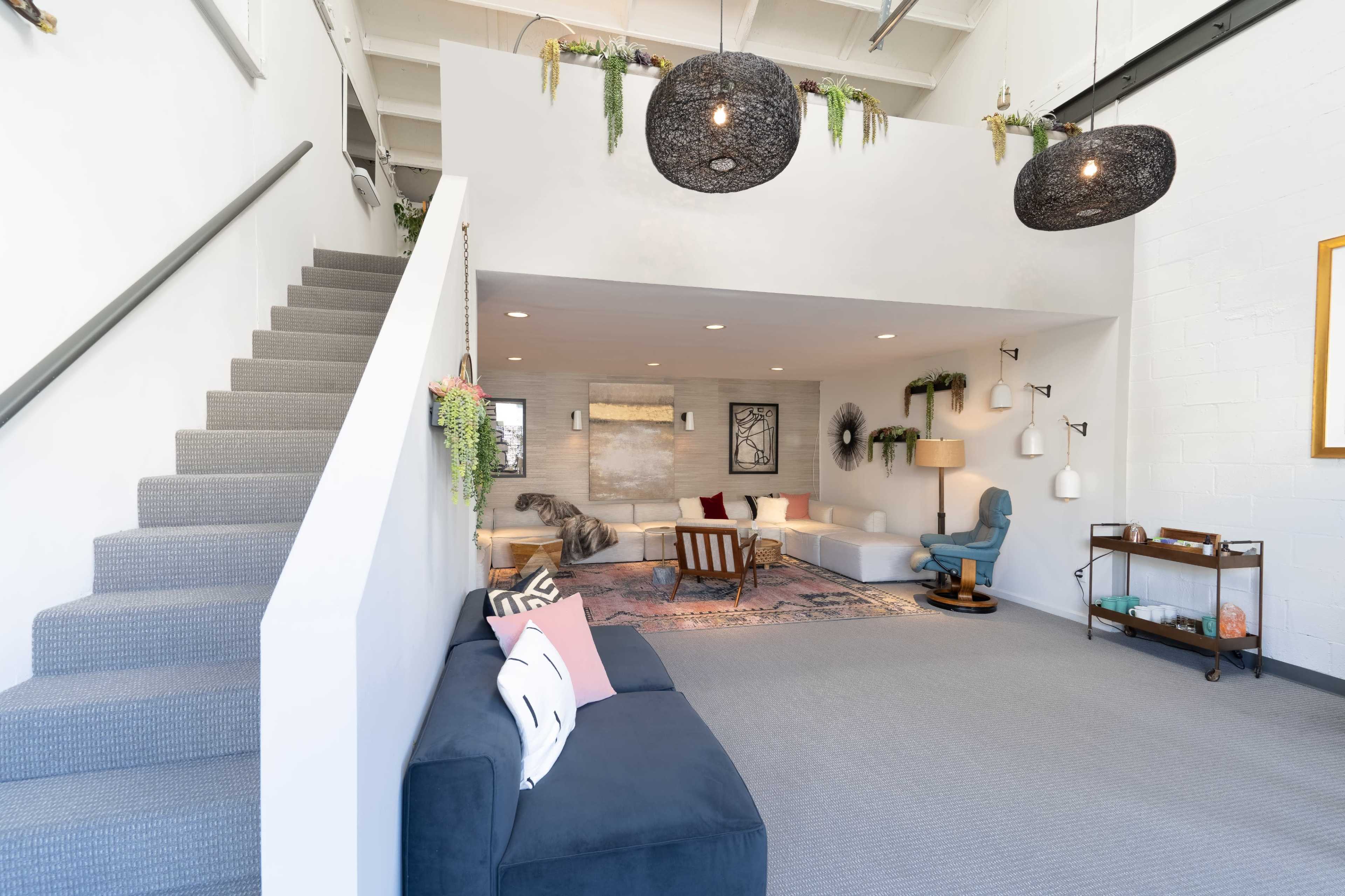 A modern, open living space with a staircase, cozy seating areas, and decorative lighting.