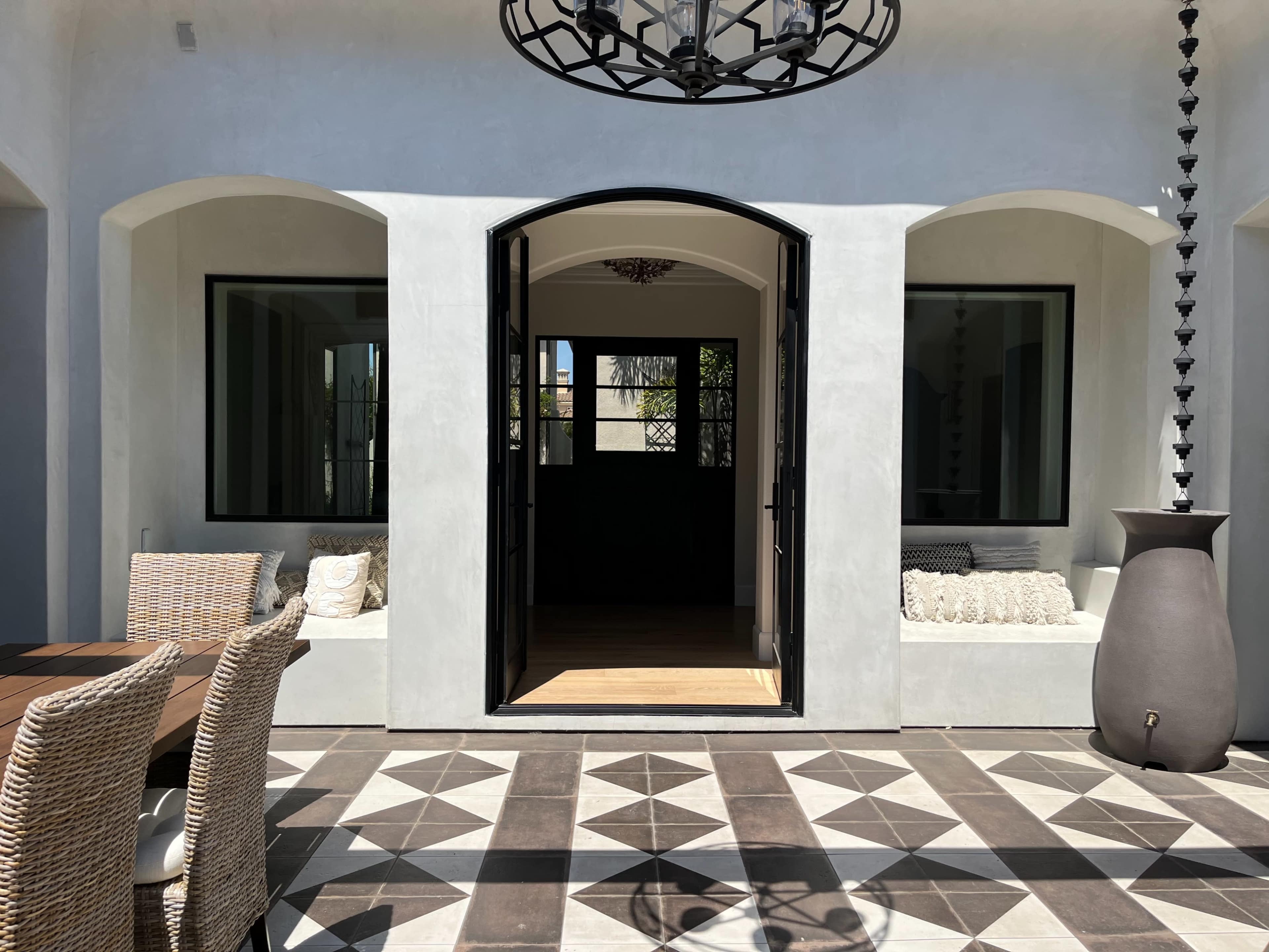 An open entrance with a view of a tiled patio and two seating areas framed by archways.