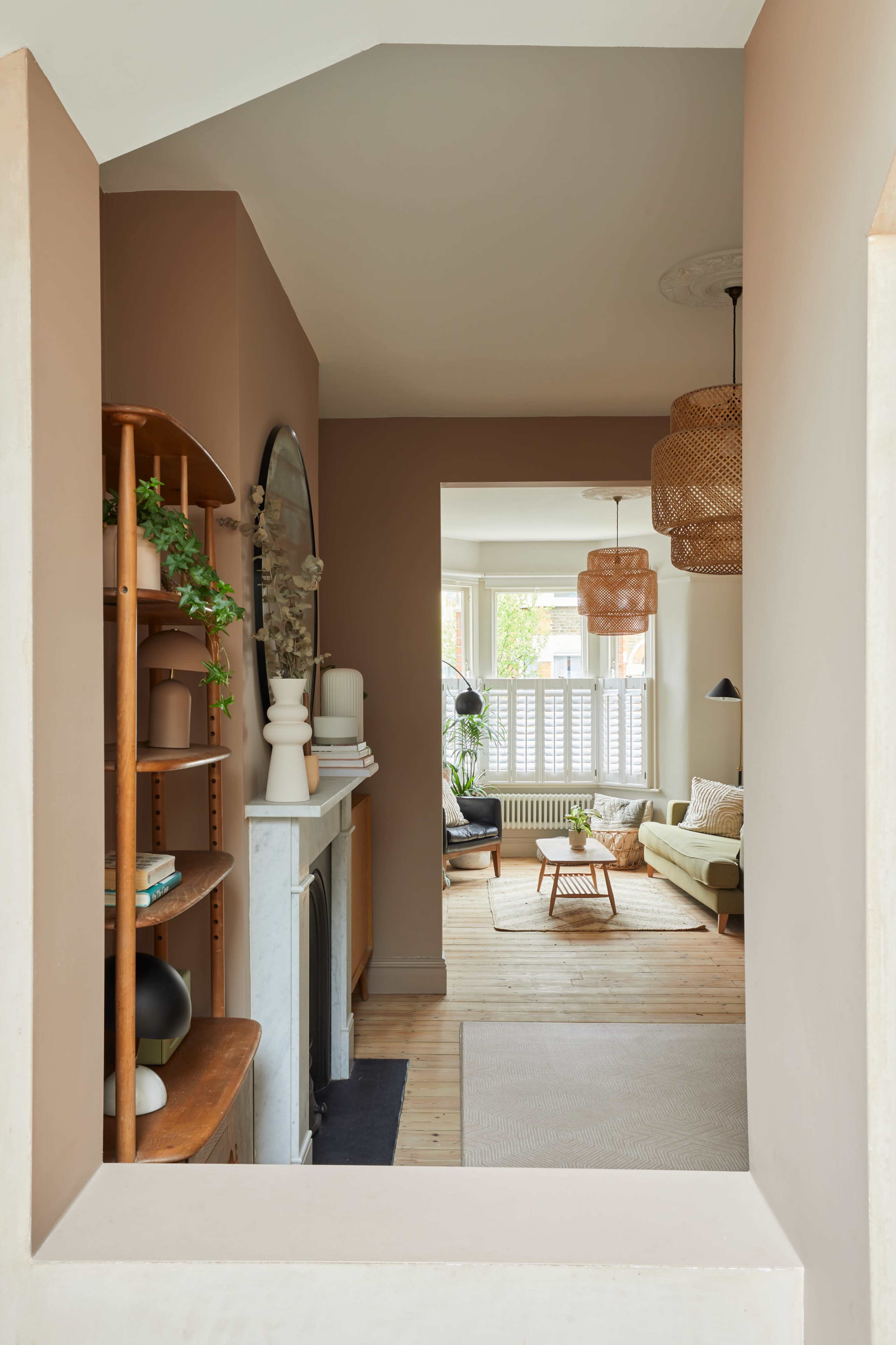 A cozy living room seen through an archway, featuring a mix of wooden furniture and soft, natural light.