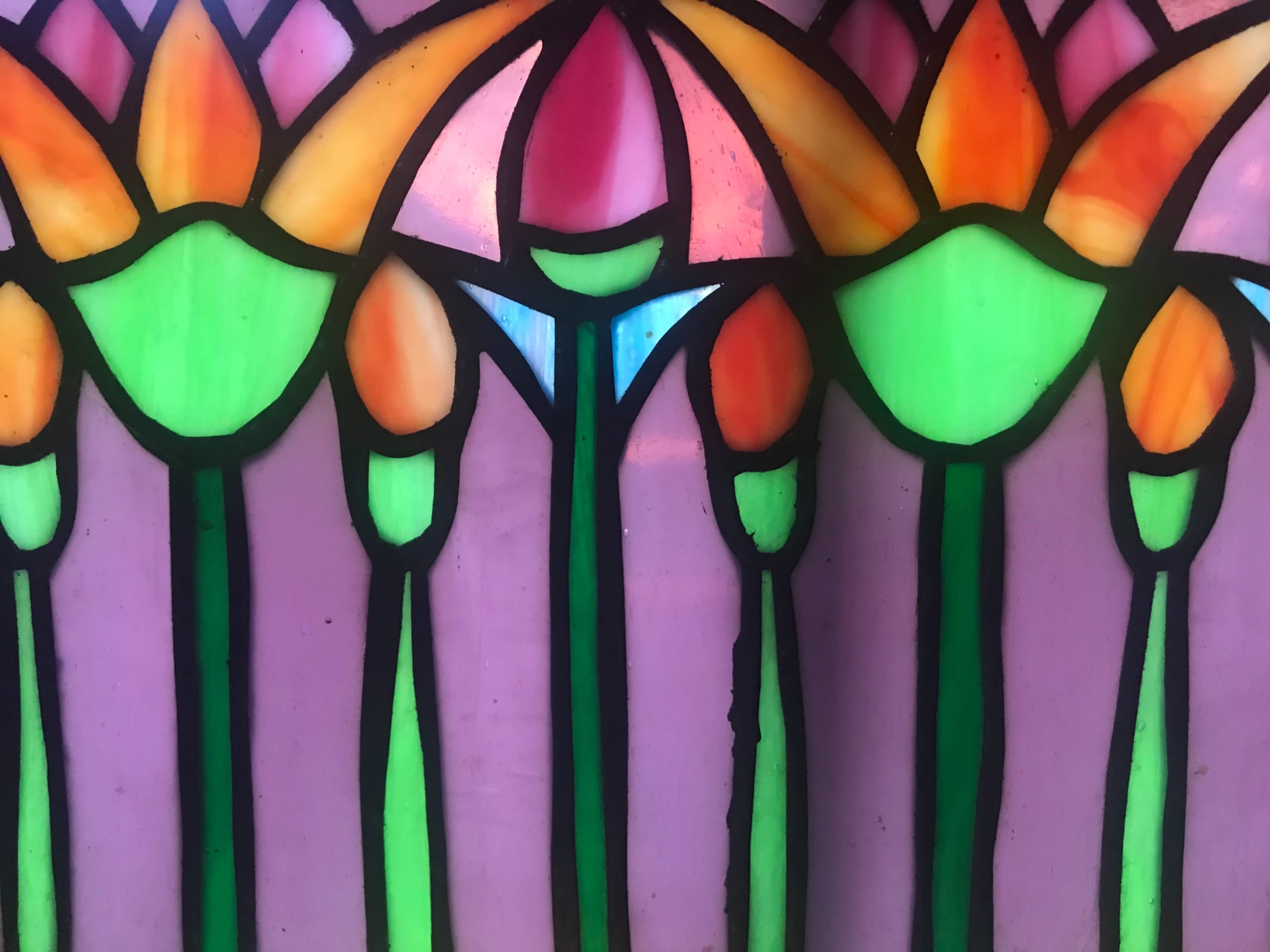 A section of stained glass featuring a pattern of colorful flowers and leaves.