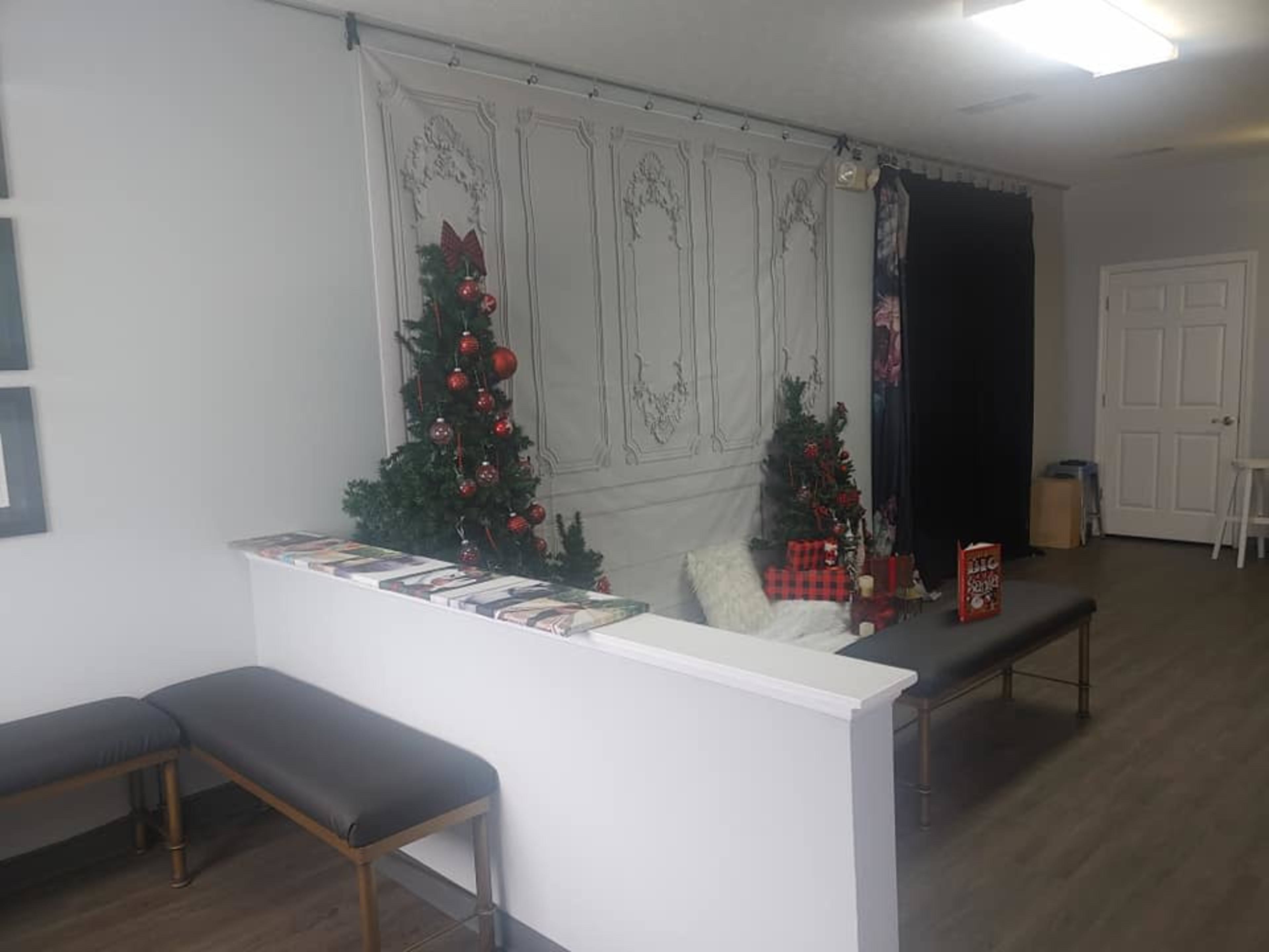 A waiting area with two decorated Christmas trees flanking a white reception desk and a seating arrangement.