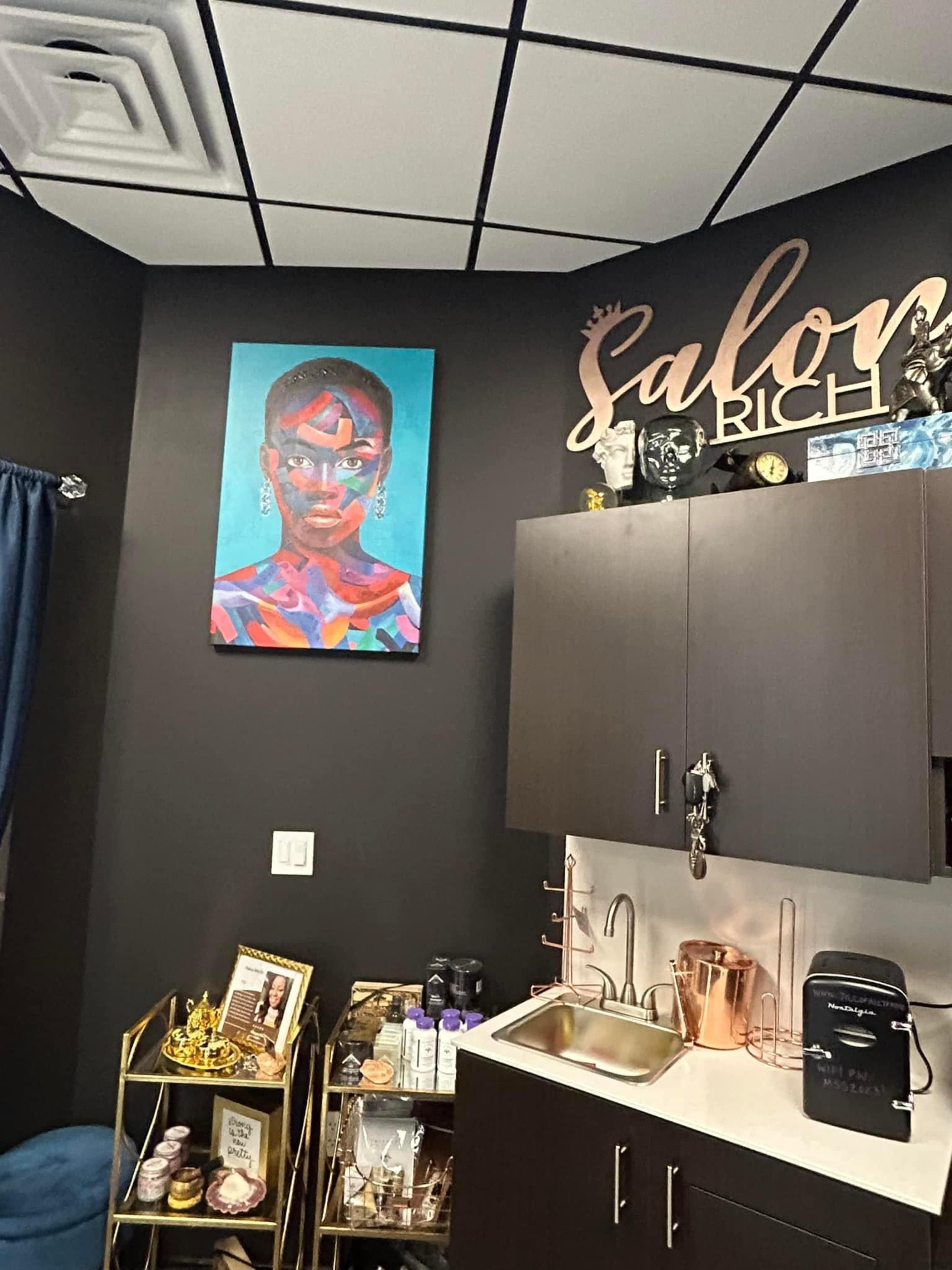 The image shows a salon interior featuring a colorful painting of a woman on the wall, a countertop with a sink, and various decorative items displayed on shelves.