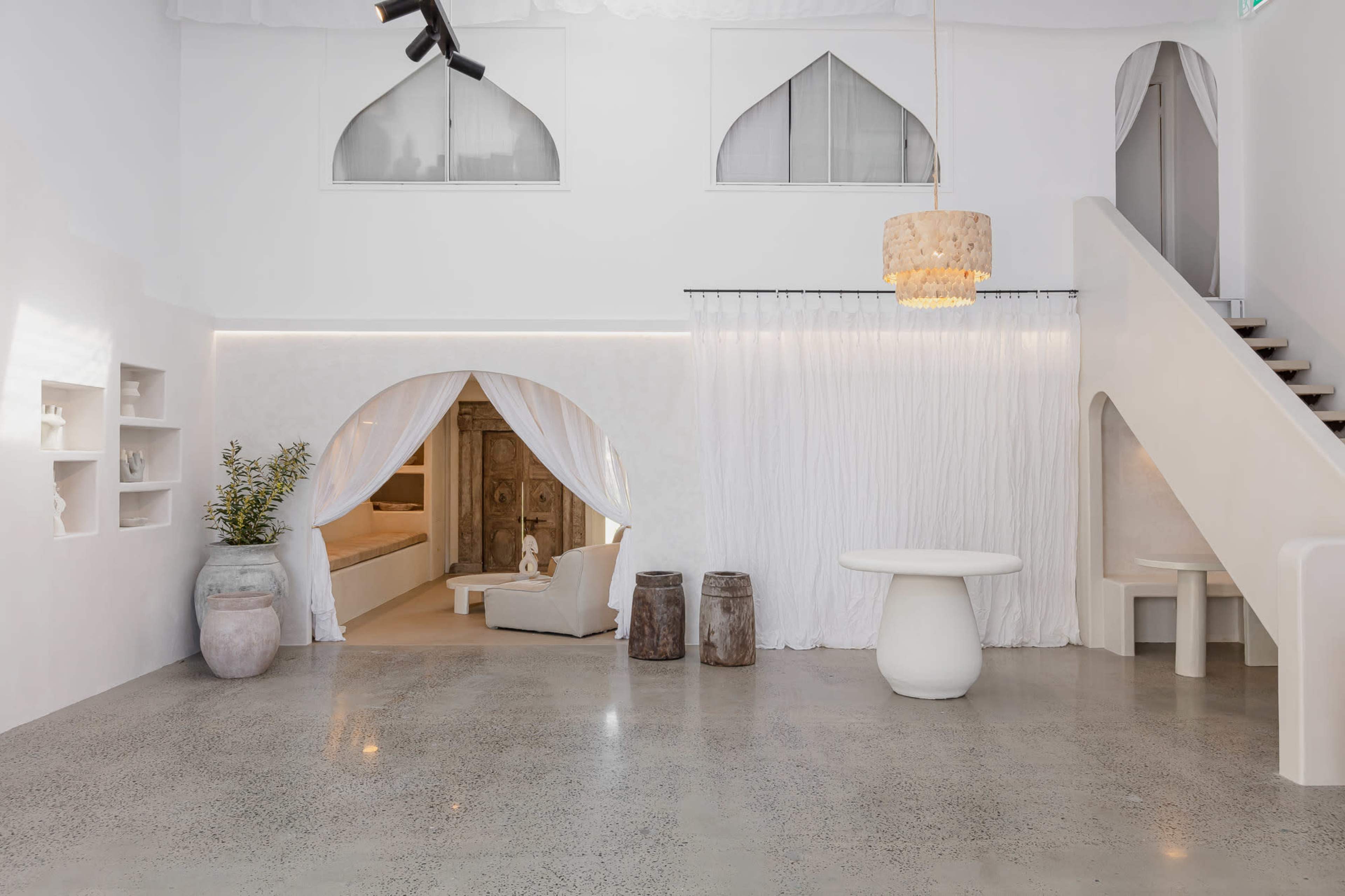 A spacious, modern interior with white walls, a minimalist decor, and a staircase leading to an upper level.