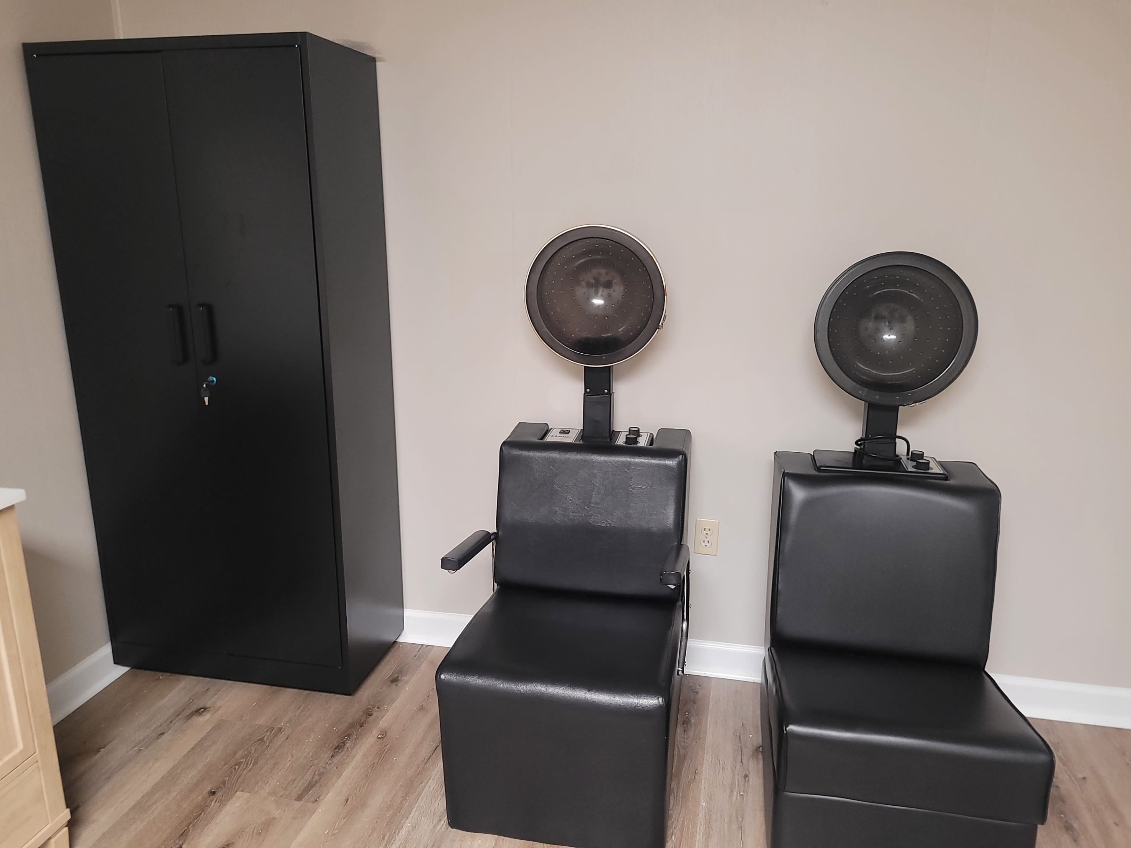The image shows a room with two black hair drying stations and a black cabinet against the wall.