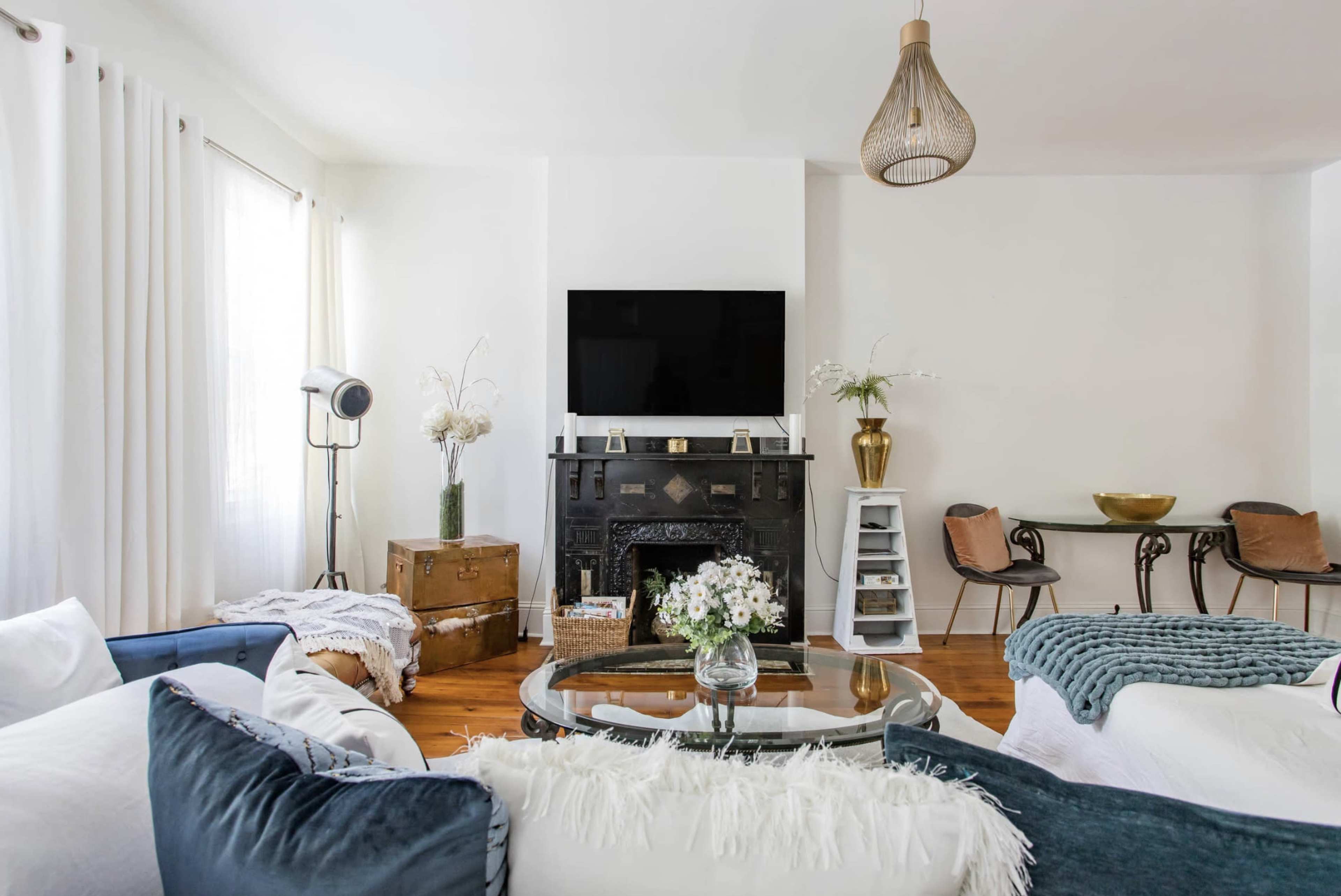 A modern living room featuring a black fireplace, a television mounted above, a glass coffee table, and a mix of decorative elements.