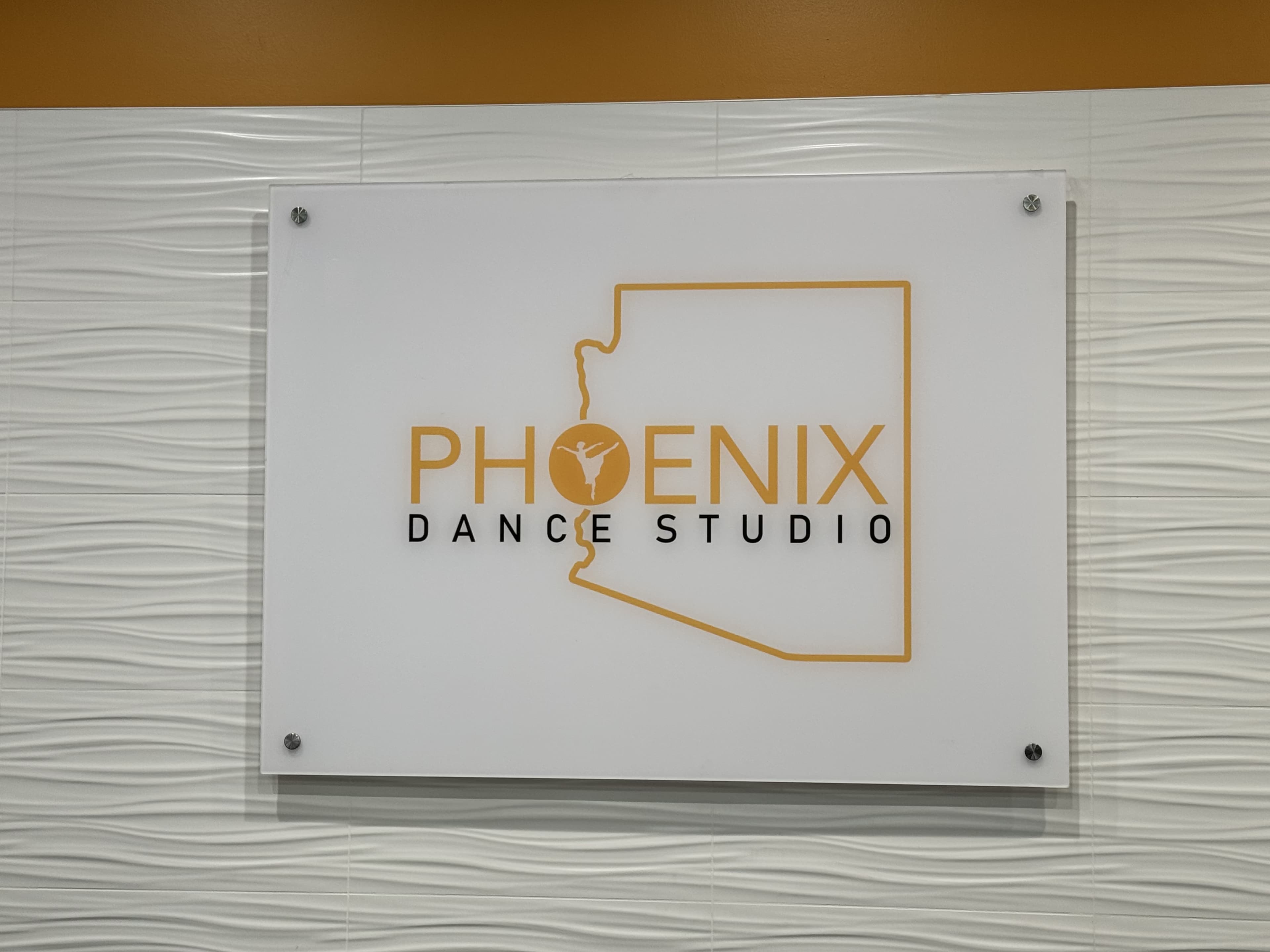A wall-mounted sign for "Phoenix Dance Studio," featuring a design of the state of Arizona.