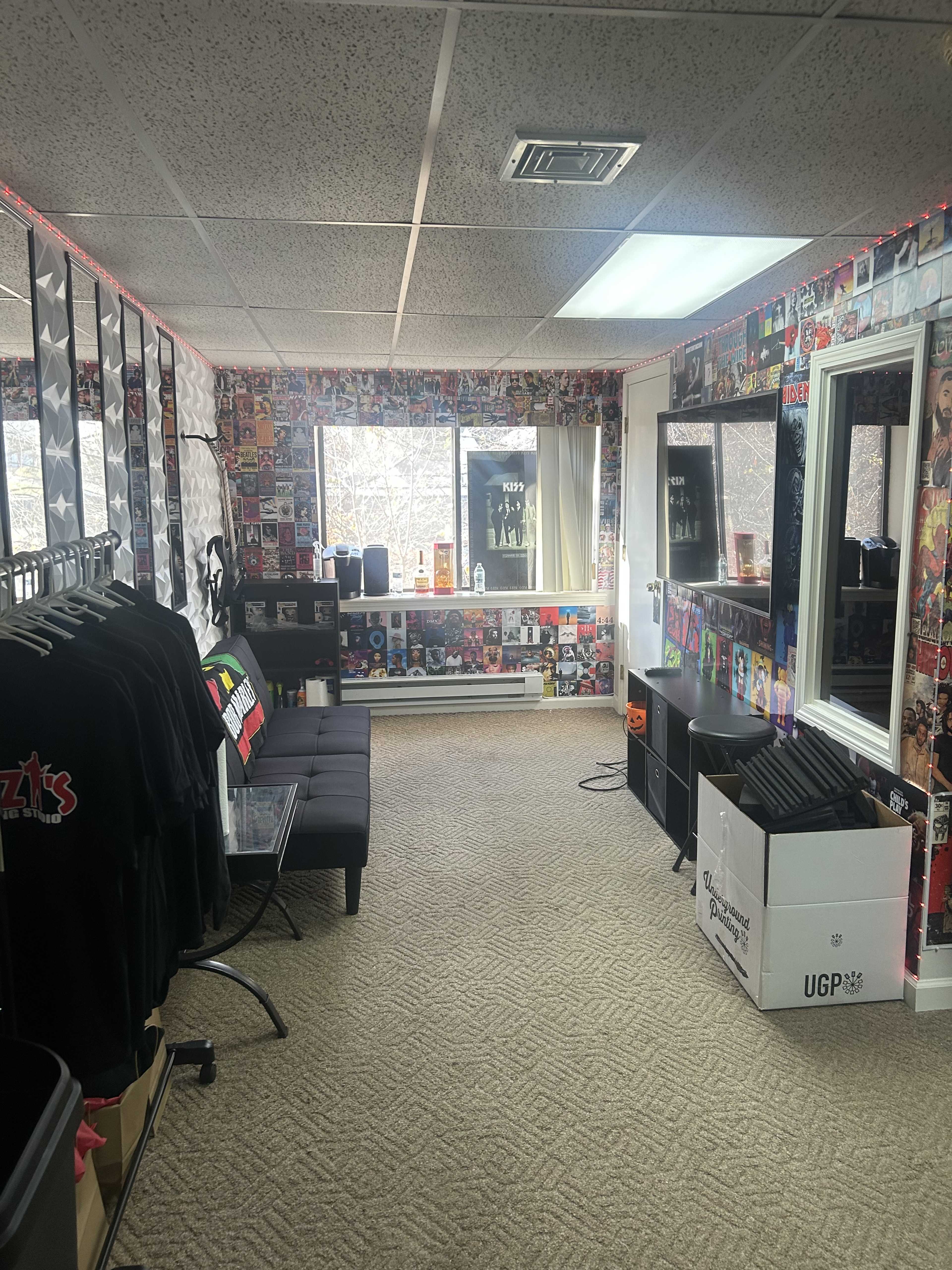 A room with wall-mounted posters, a black couch, mirrors, and displayed merchandise.