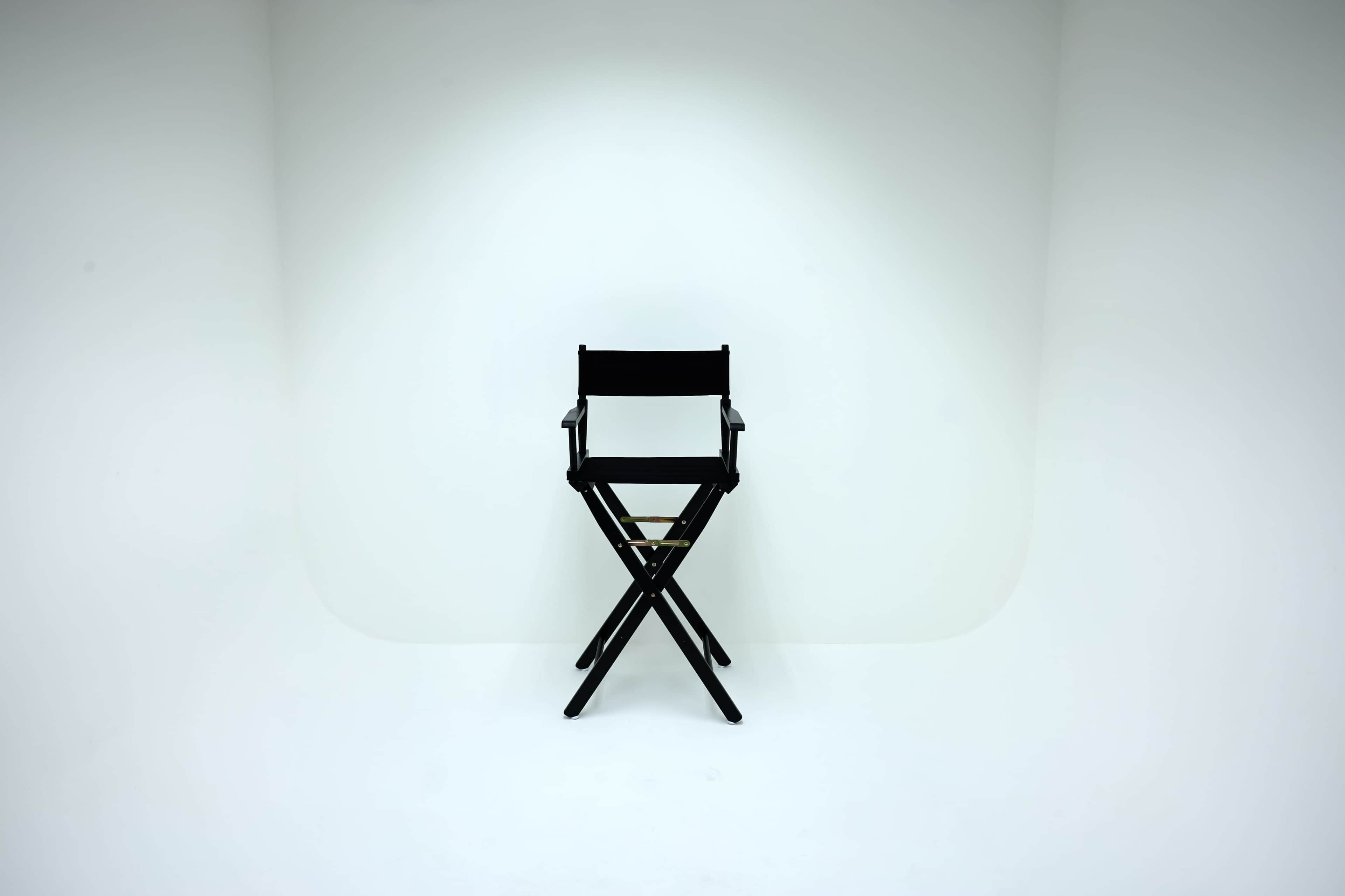 A black director's chair is positioned in the center of a plain white background.