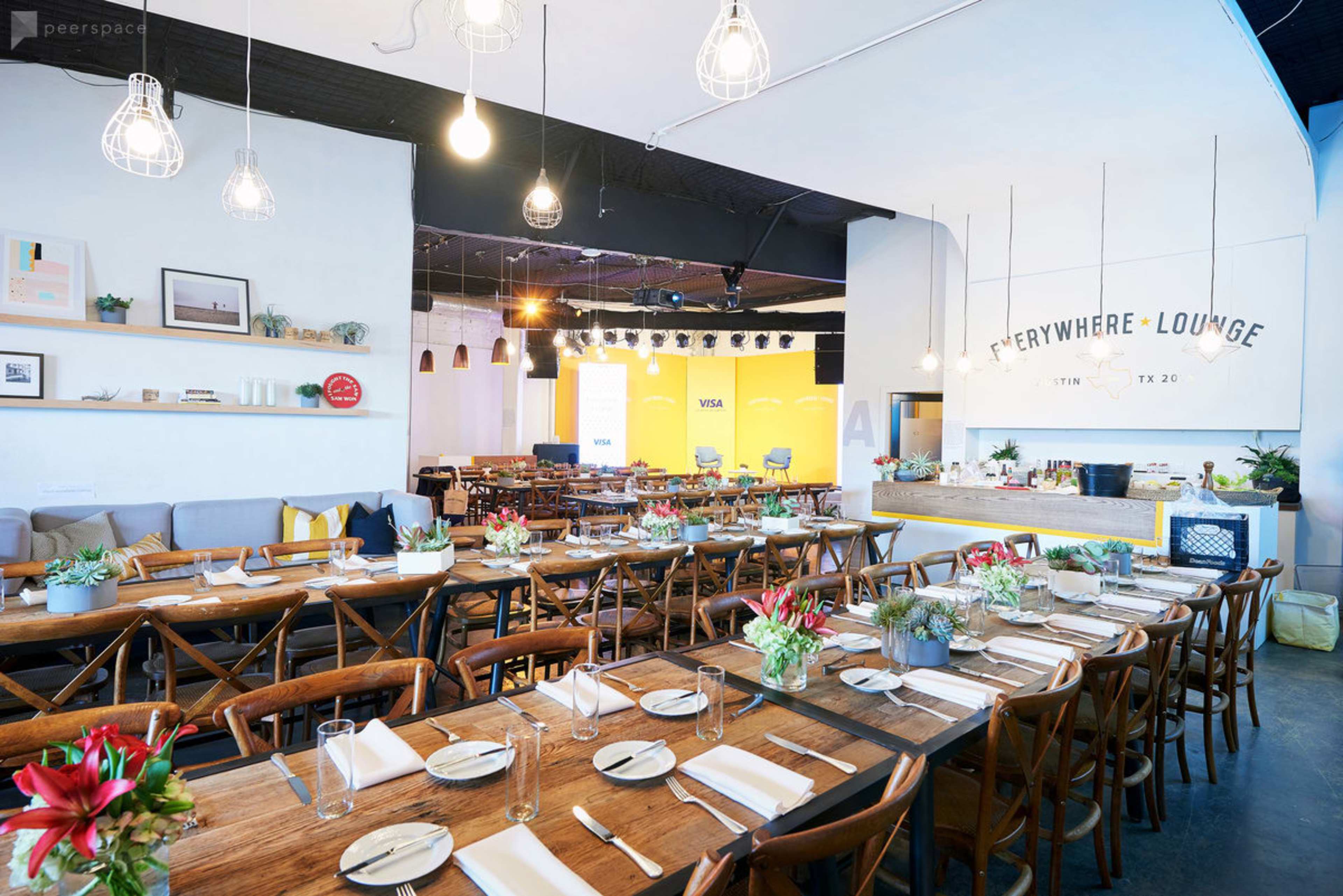 The image shows a spacious restaurant interior with wooden tables, chairs, and modern lighting fixtures.
