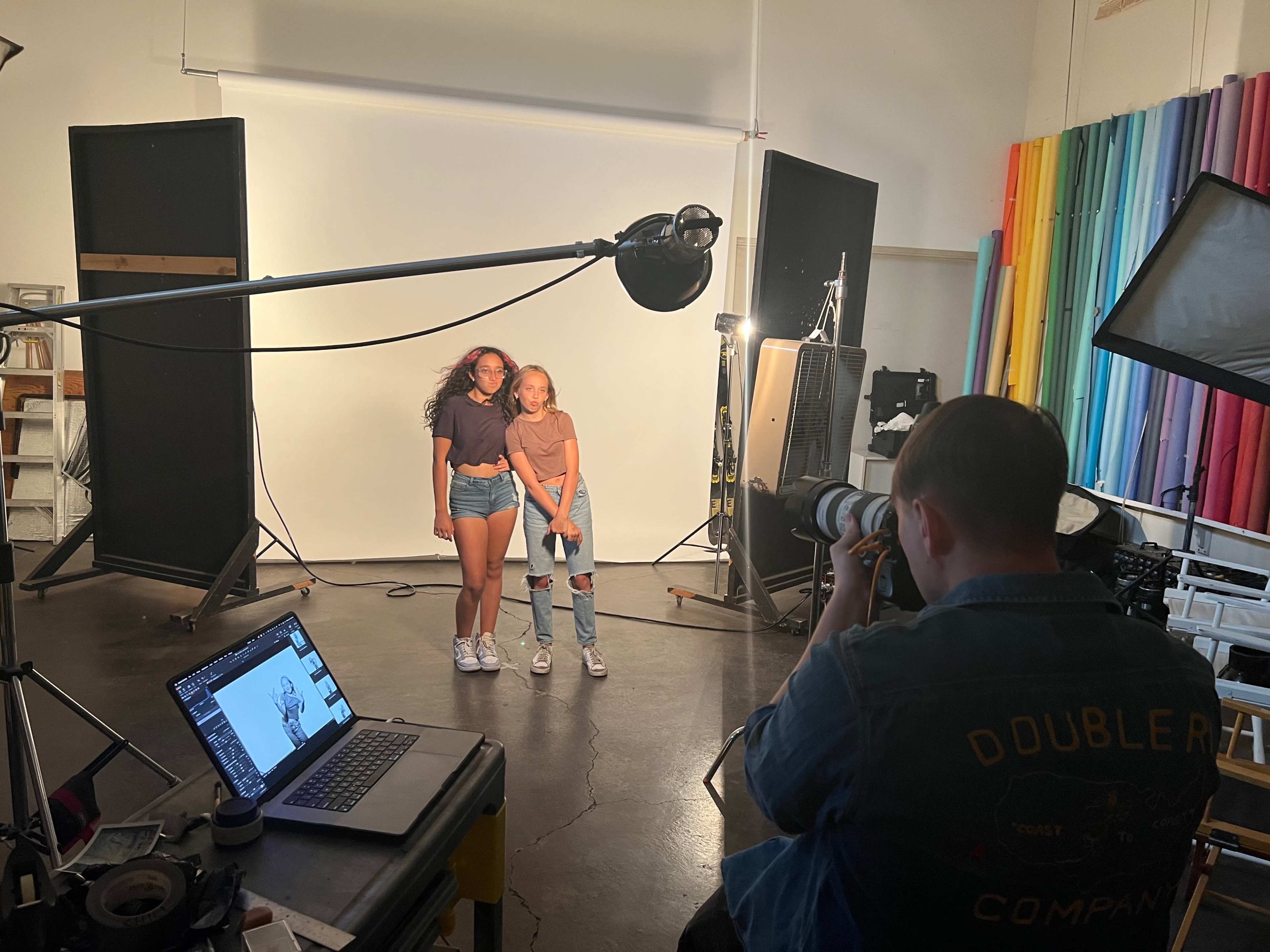 A photographer is capturing a portrait of two girls in a studio setup with a backdrop and multiple lights.