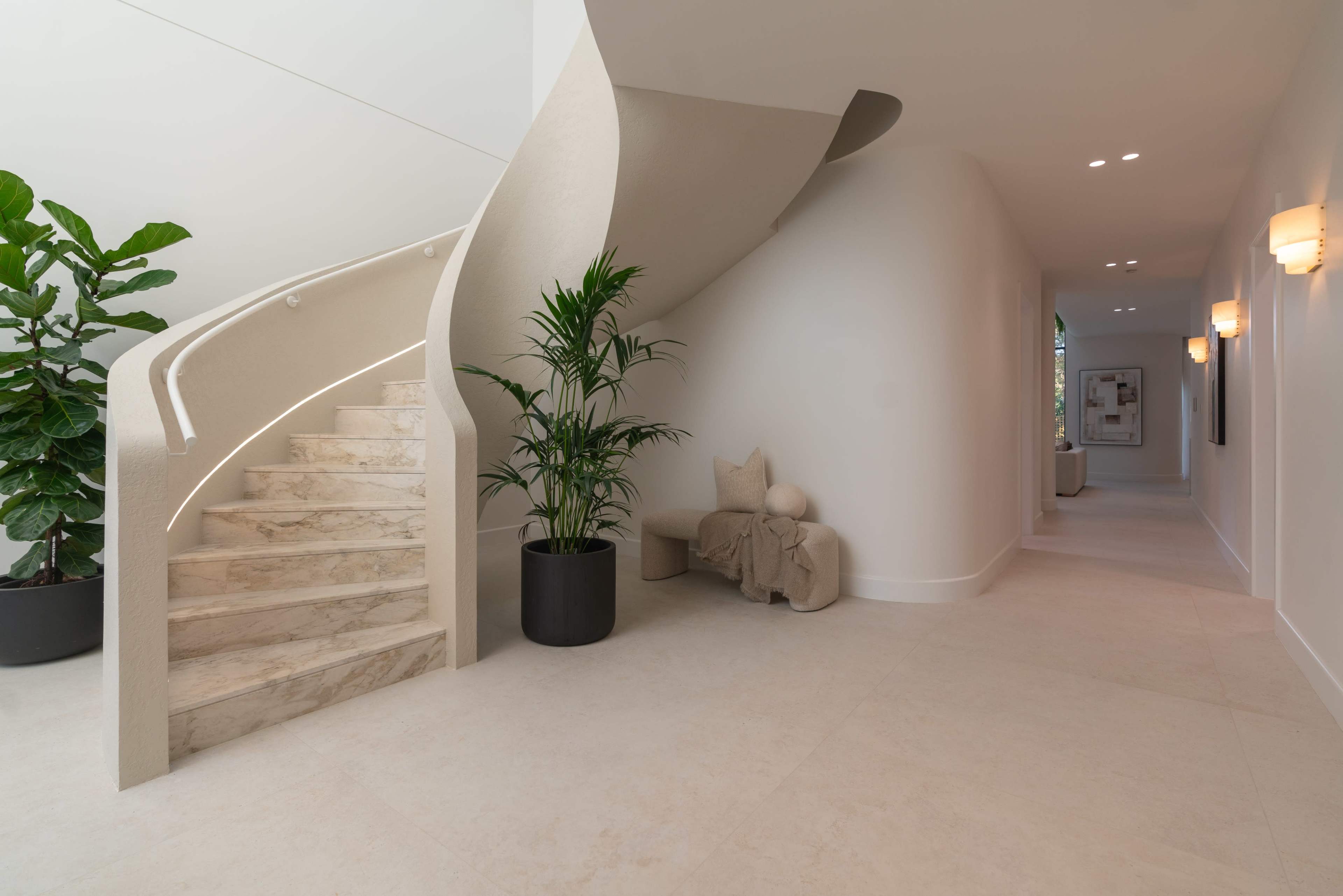 The image features a modern interior with a spiral staircase, decorative plants, and a minimalist design.