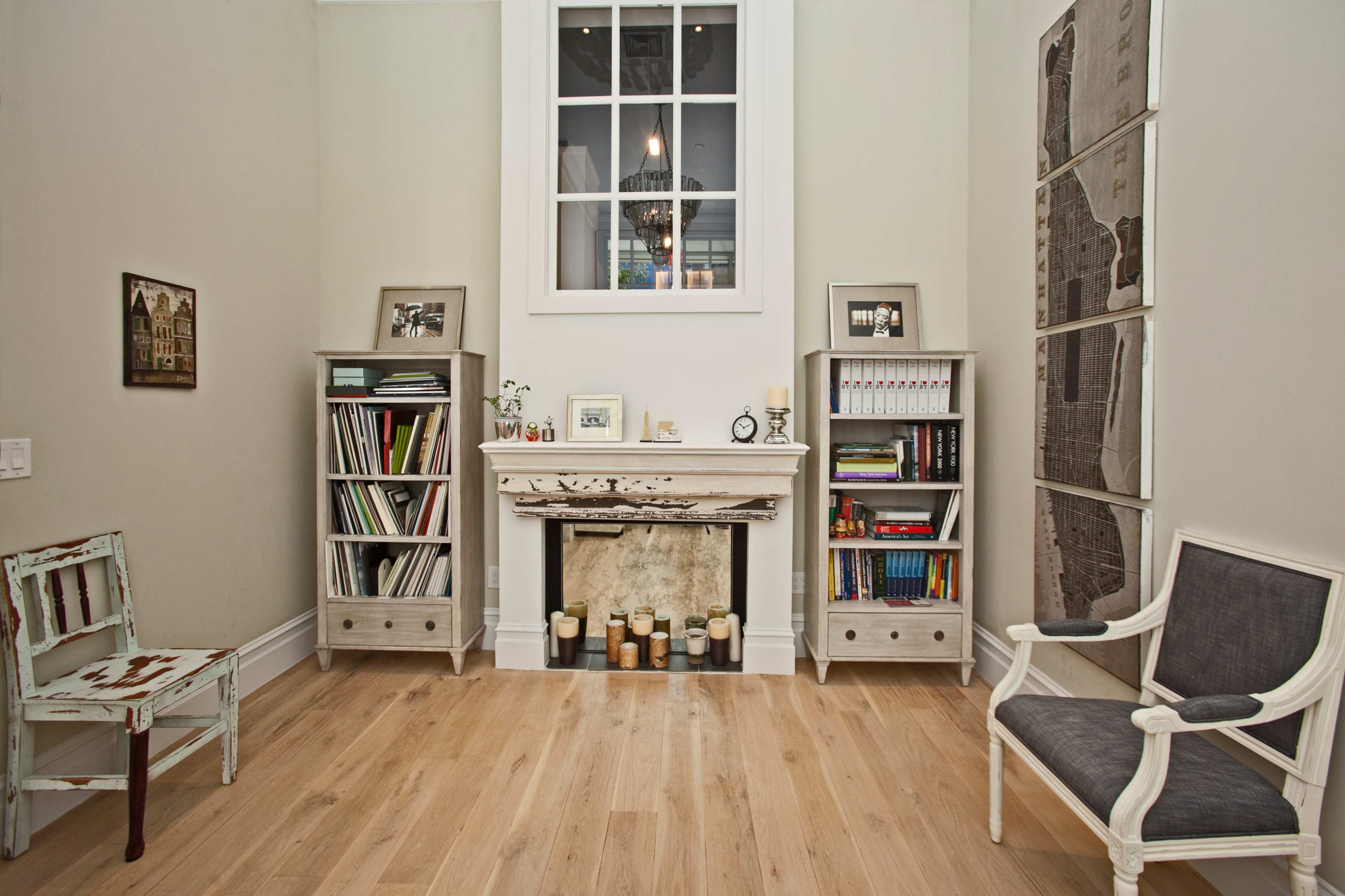 A cozy corner of a room features a fireplace flanked by two bookcases filled with books and decor, along with a wooden chair and an elegant armchair.