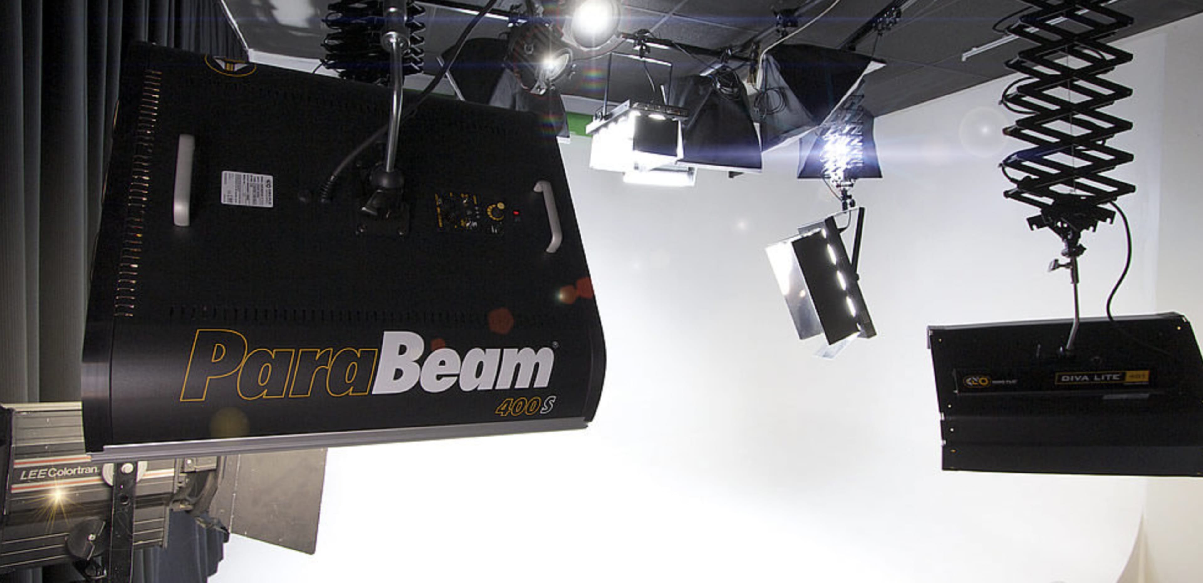 A studio lighting setup with various overhead lights and equipment arranged above a white backdrop.