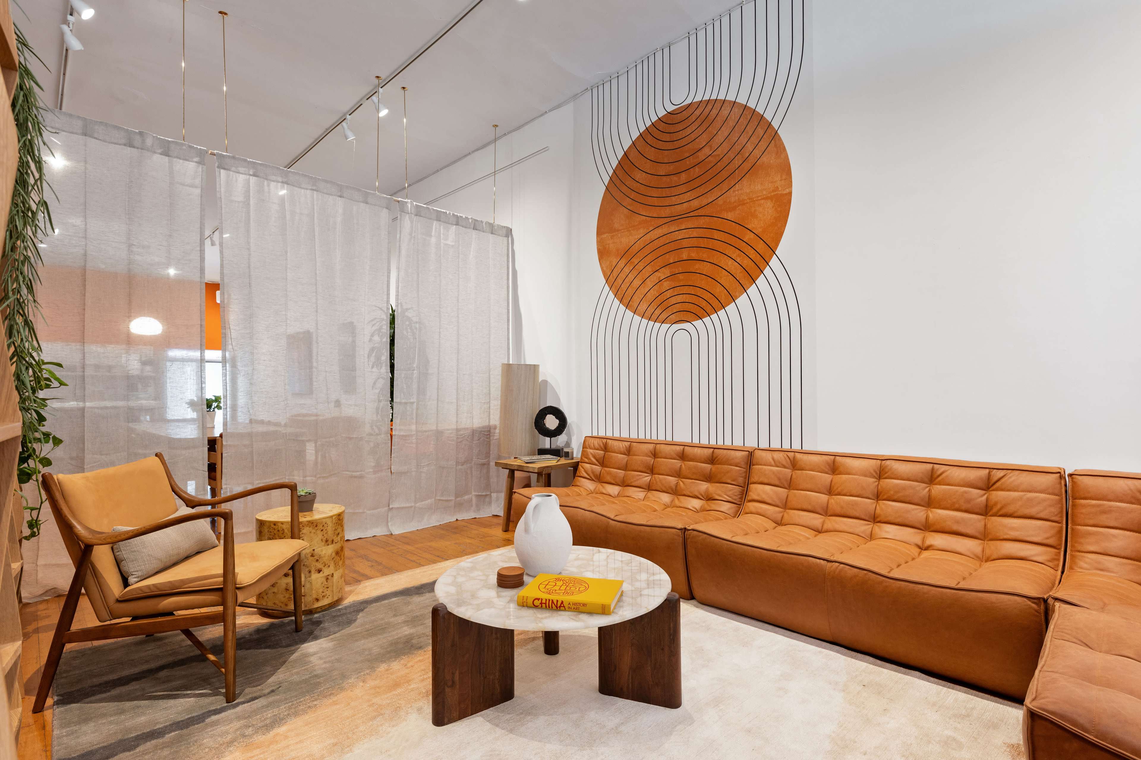 A modern living room with a large tan sectional sofa, a round coffee table, and a geometric wall design featuring a circular motif.