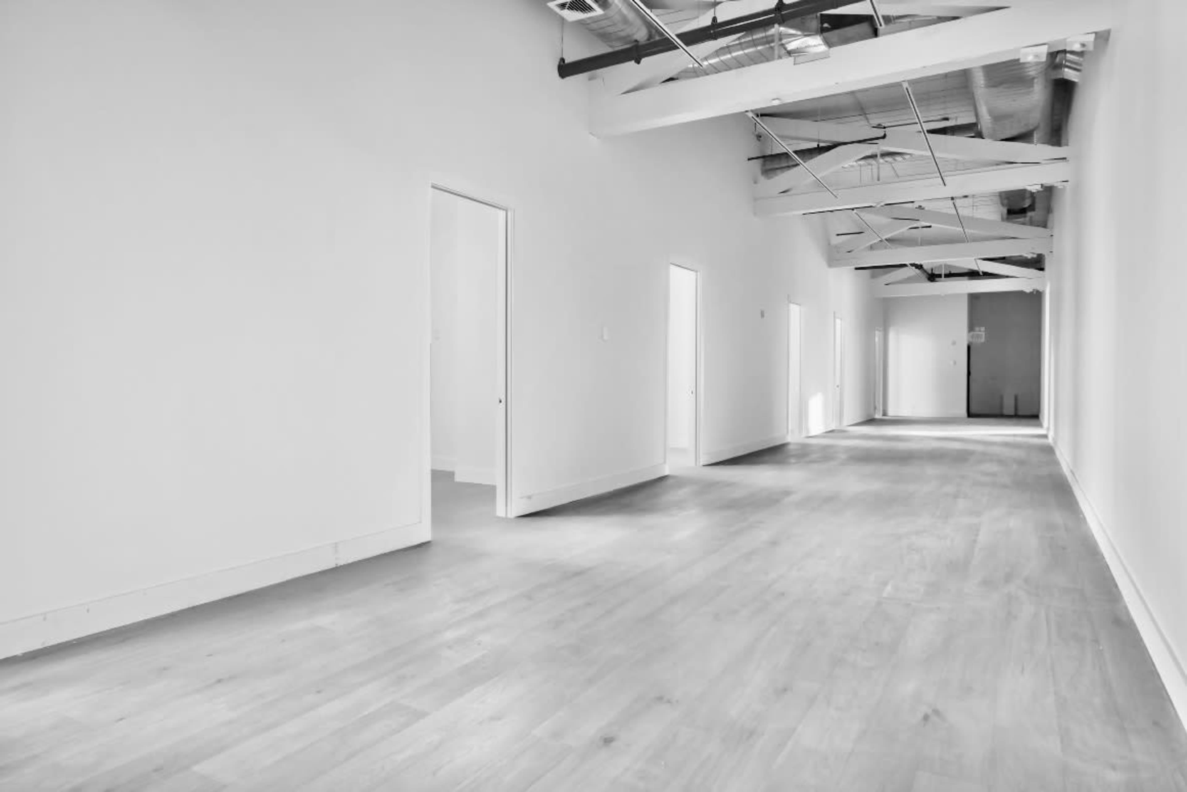 A long, empty hallway with white walls and doors on either side.