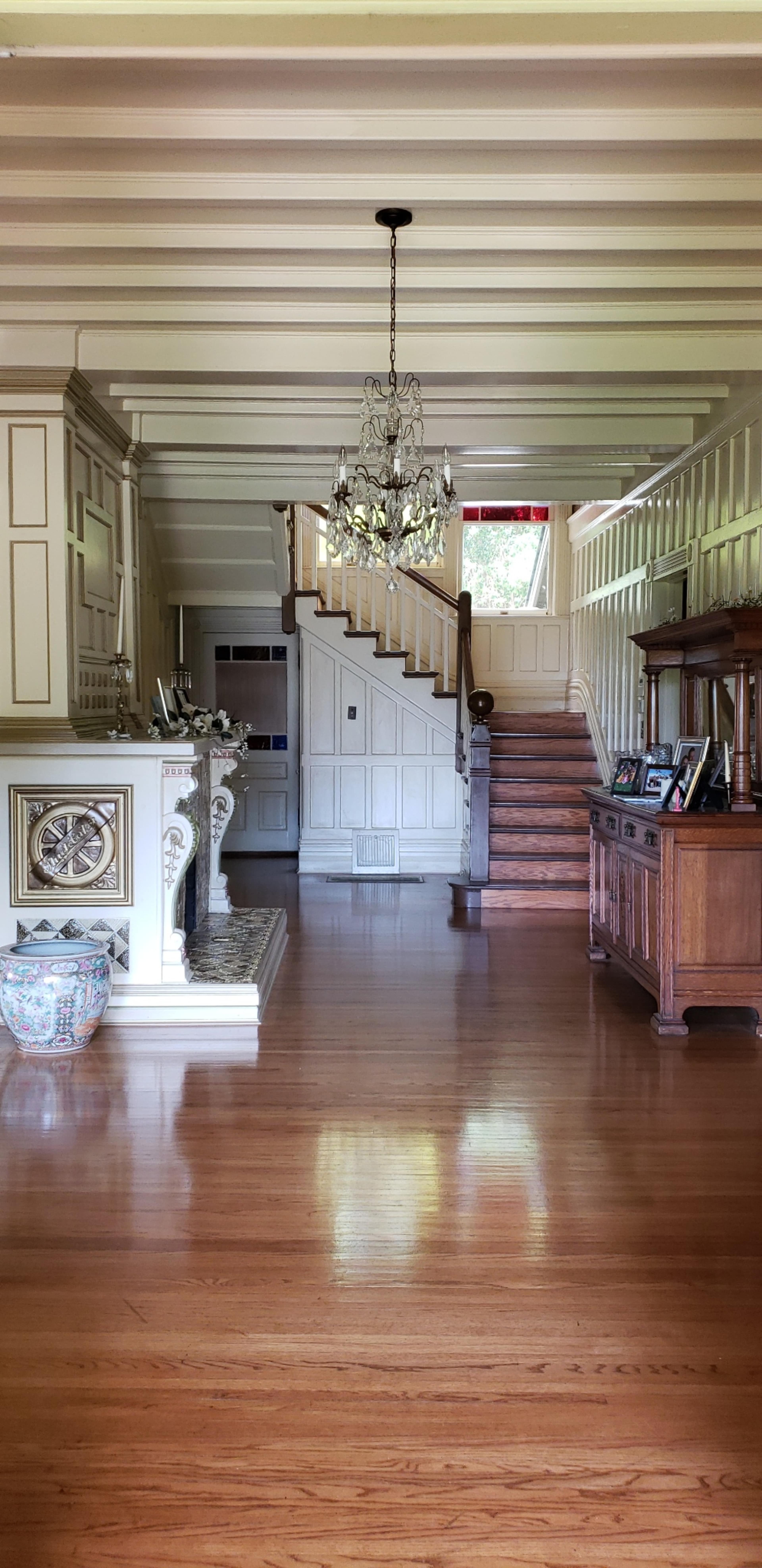 A spacious foyer with a staircase leading to the upper level, a chandelier hanging from the ceiling, and decorative furnishings along the walls.