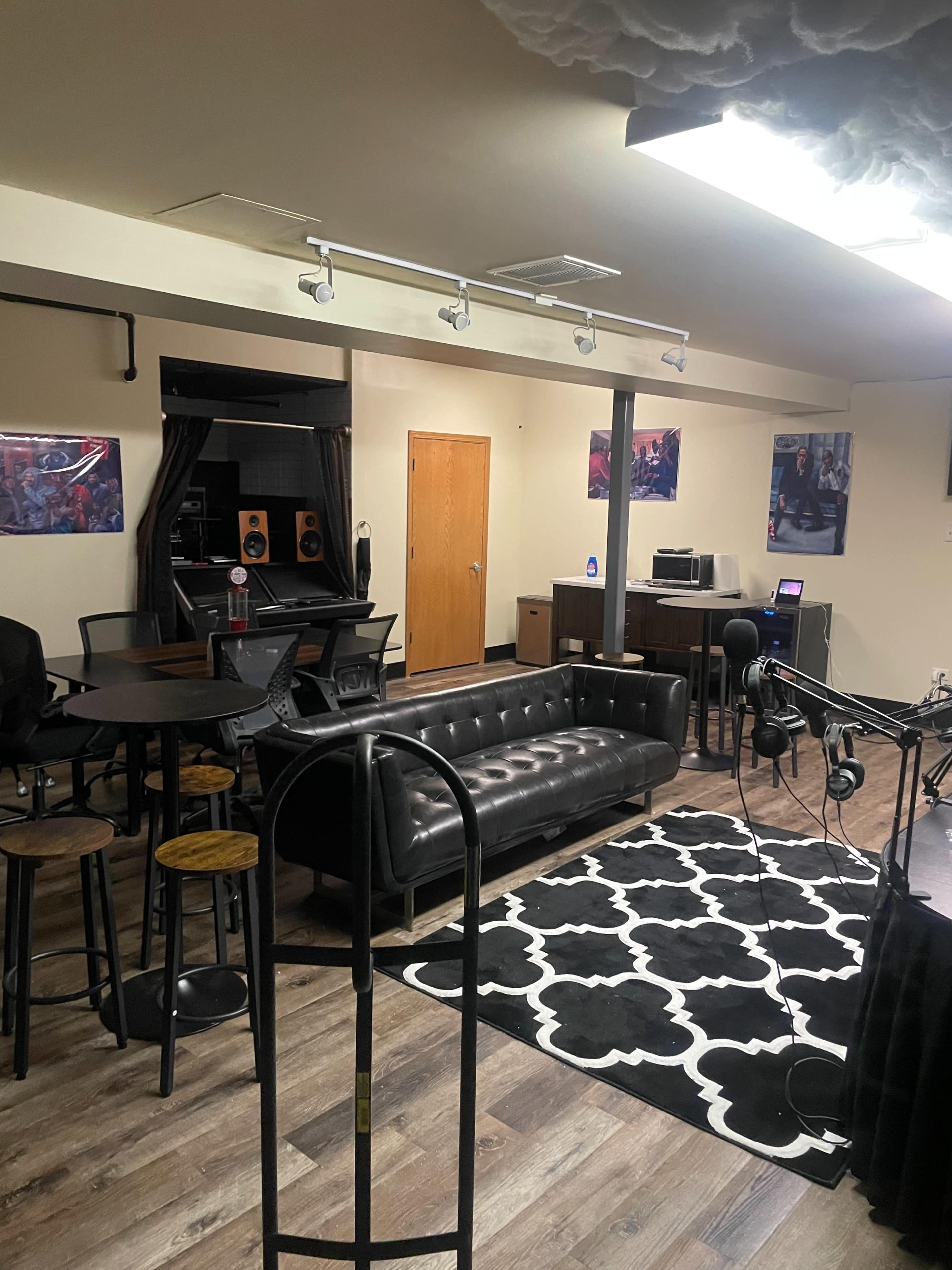 A modern recording studio lounge featuring seating, a black and white area rug, and audio equipment.