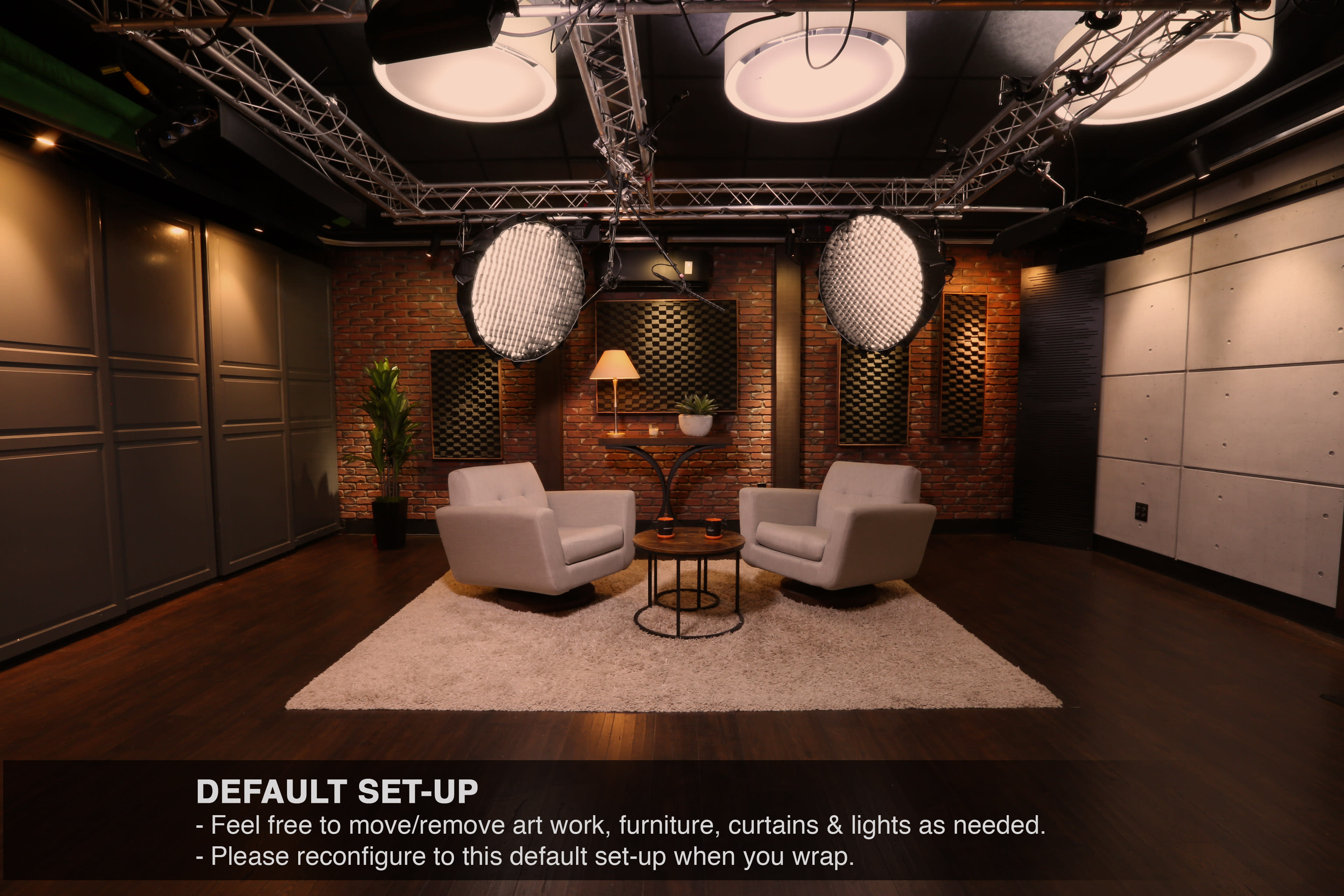 The image shows a modern studio setup with two white armchairs facing each other on a circular rug, accompanied by a coffee table and soft lighting.