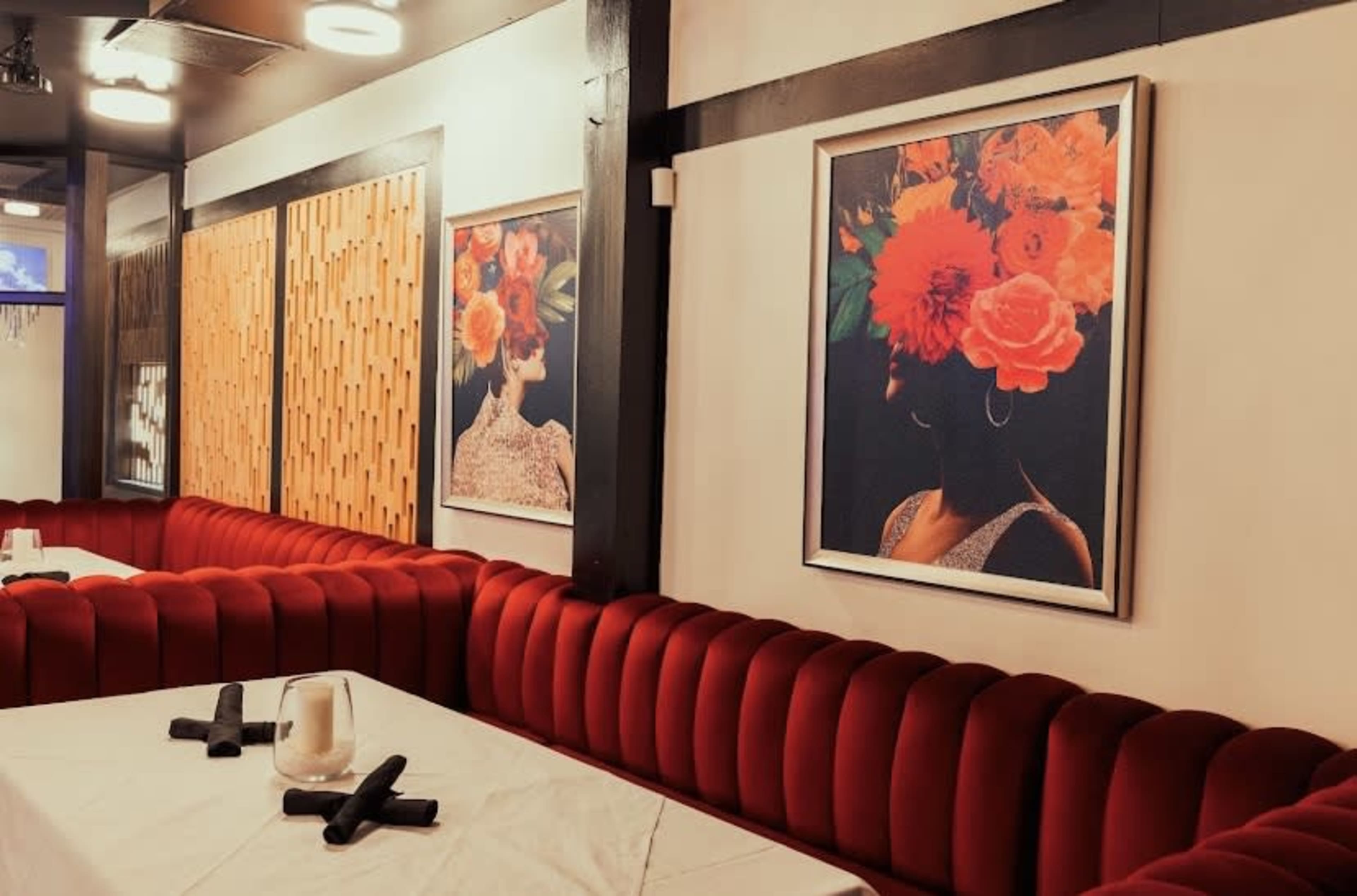 The scene features a restaurant interior with red velvet seating and framed floral portrait artworks on the walls.