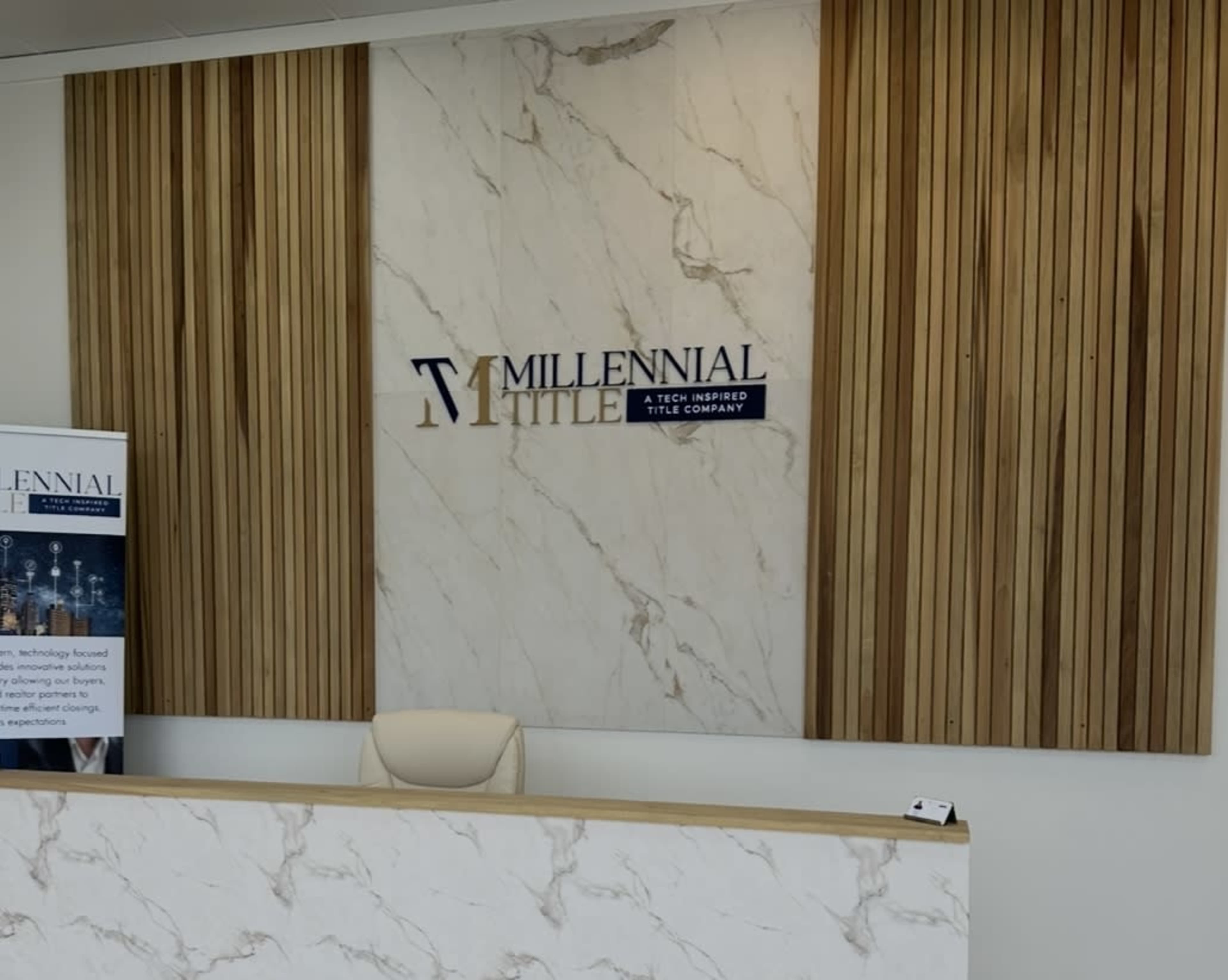 The image shows a reception area with a wooden panel backdrop and a marble feature wall displaying the "Millennial Title" logo.