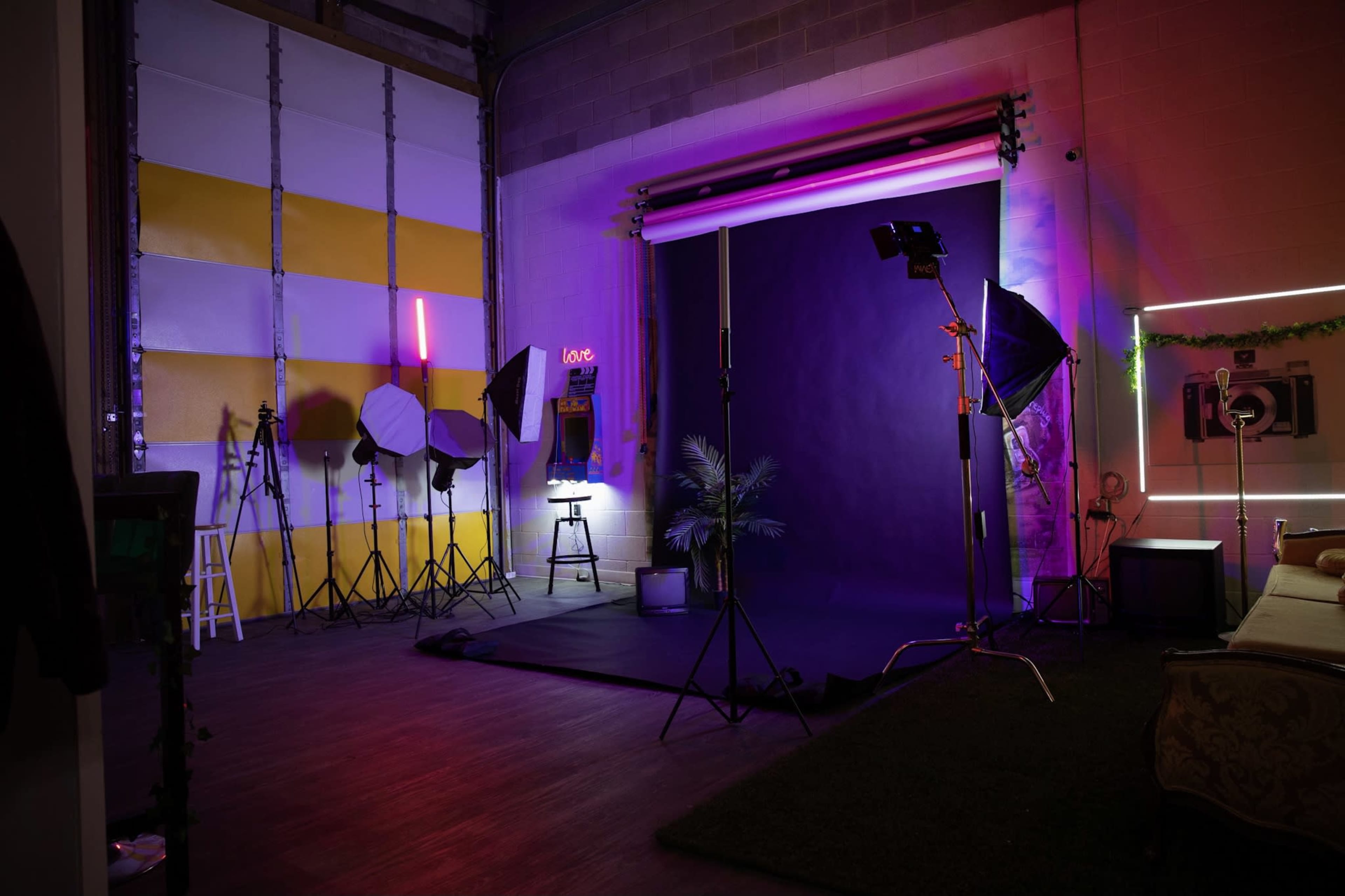 A photography studio with various lighting equipment, a black backdrop, and colorful accent lighting.