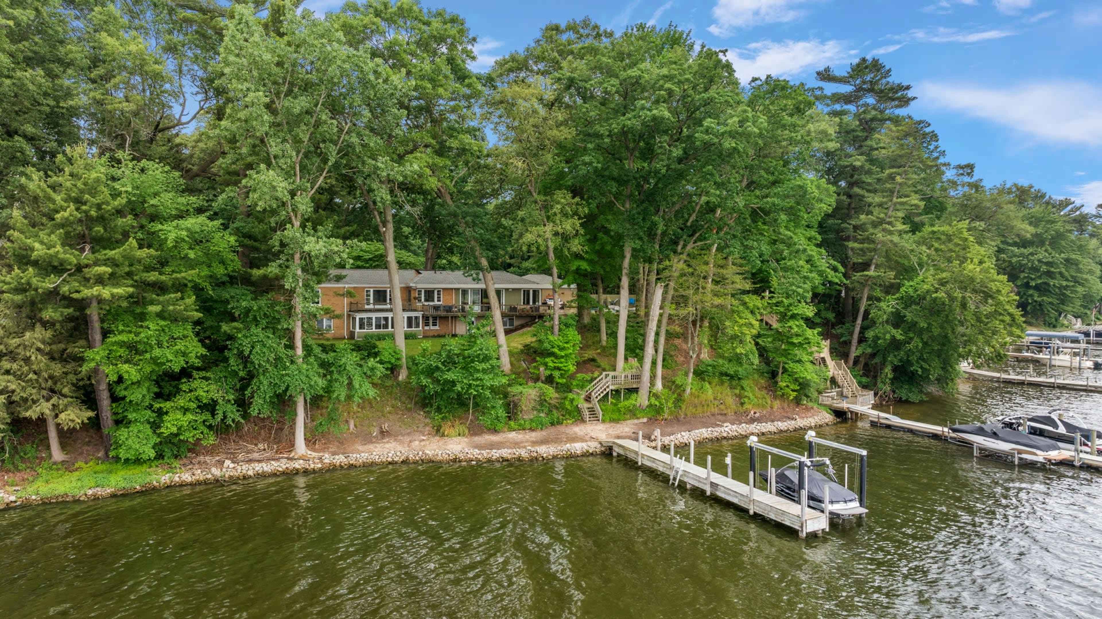 A lakeside property with a house nestled among trees and a private dock is visible from the water.