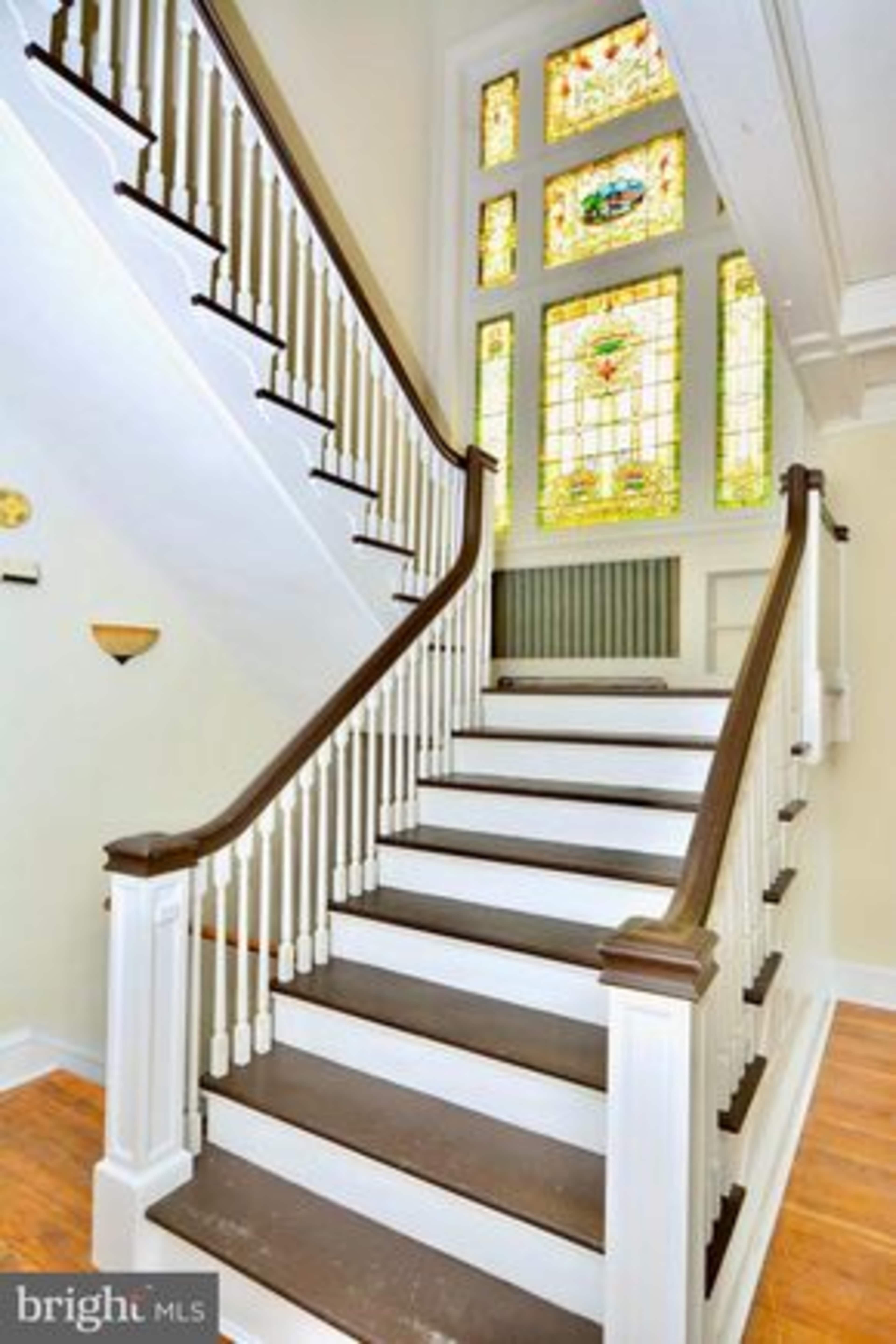 A staircase with white railings and a stained glass window above, leading to an upper level.