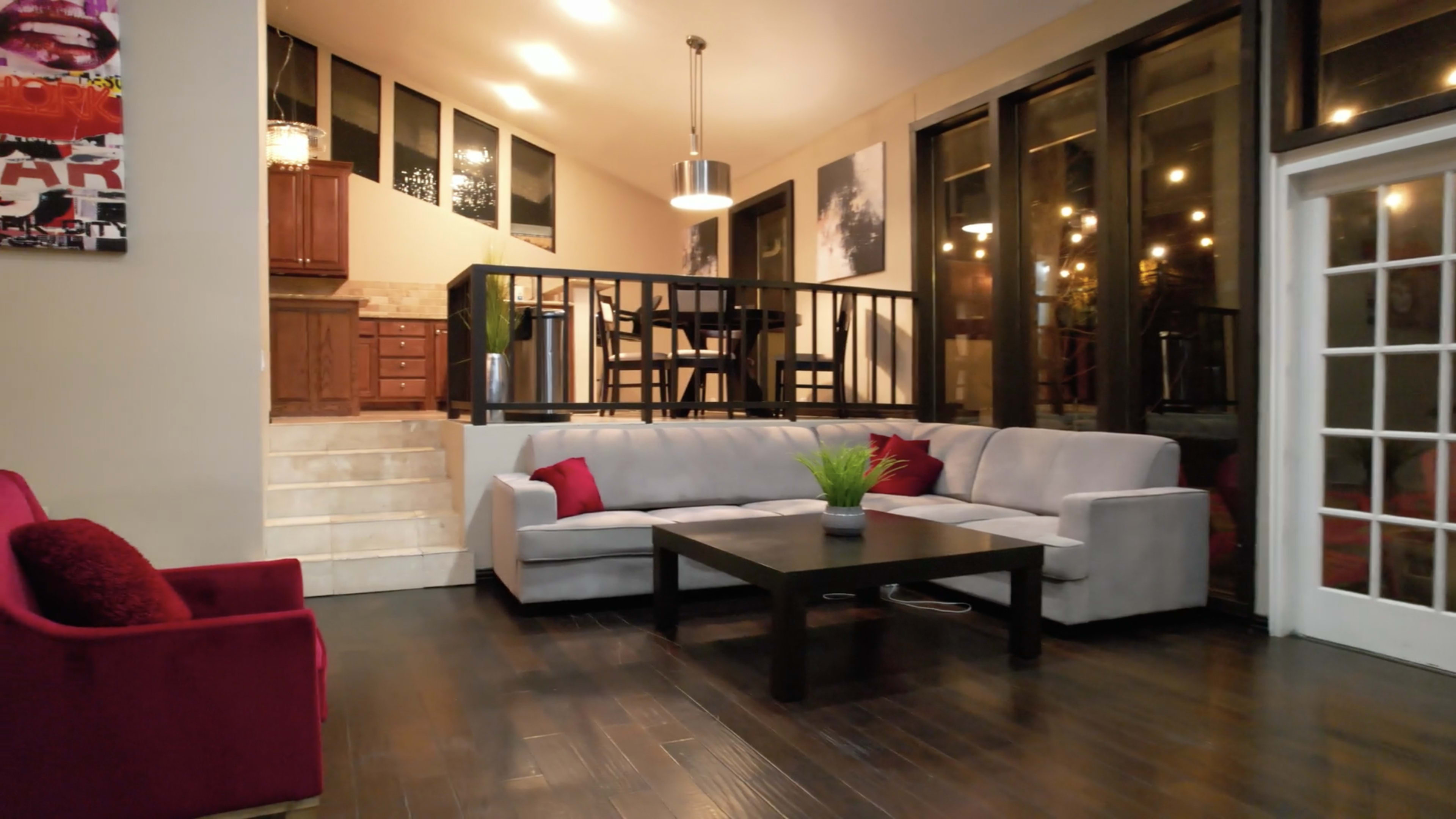 A modern living room with a gray sectional sofa, a black coffee table, and large windows allowing natural light to enter the space.