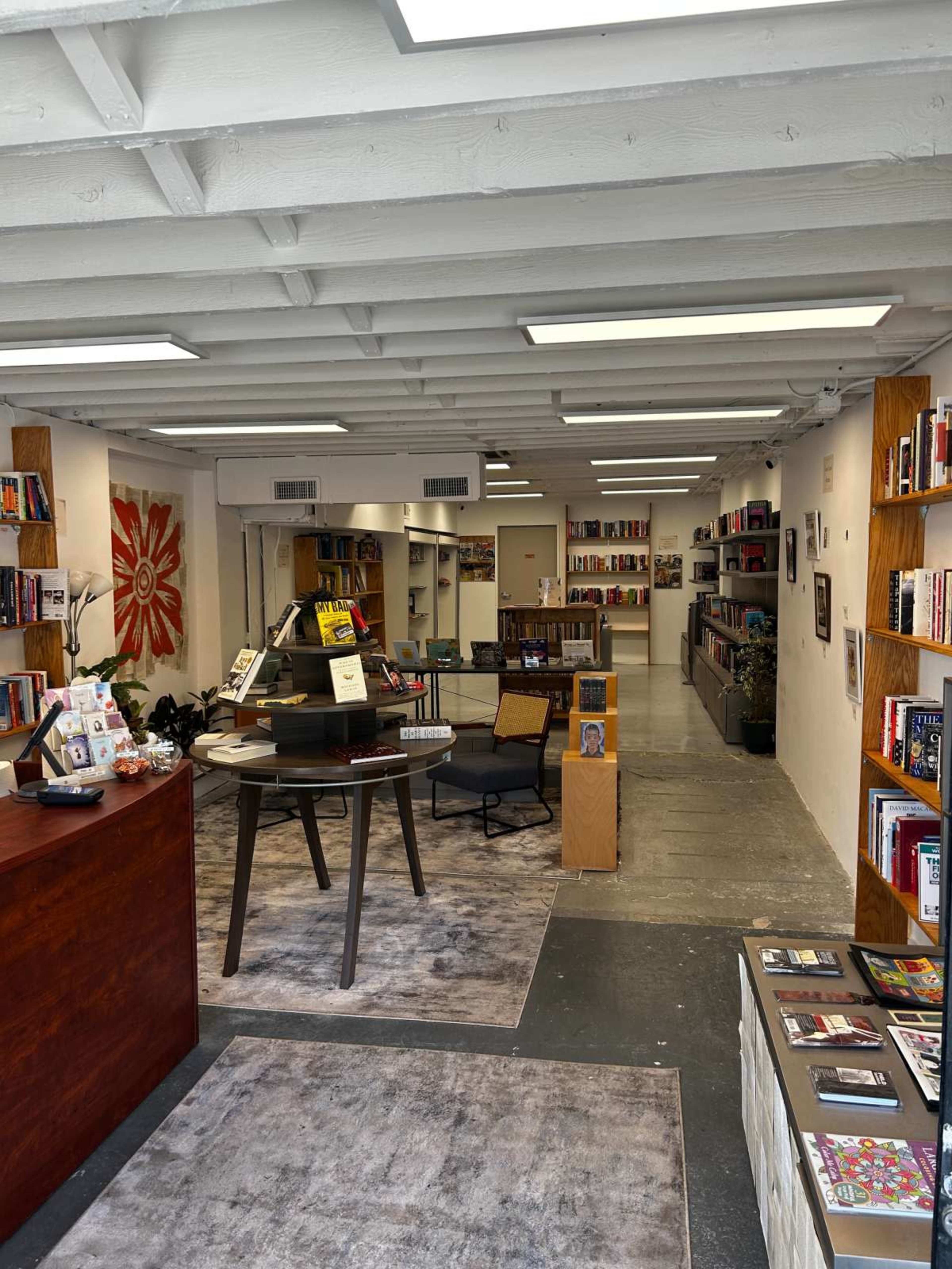 The image shows a modern bookstore interior with bookshelves lining the walls, a reception desk, and seating areas.