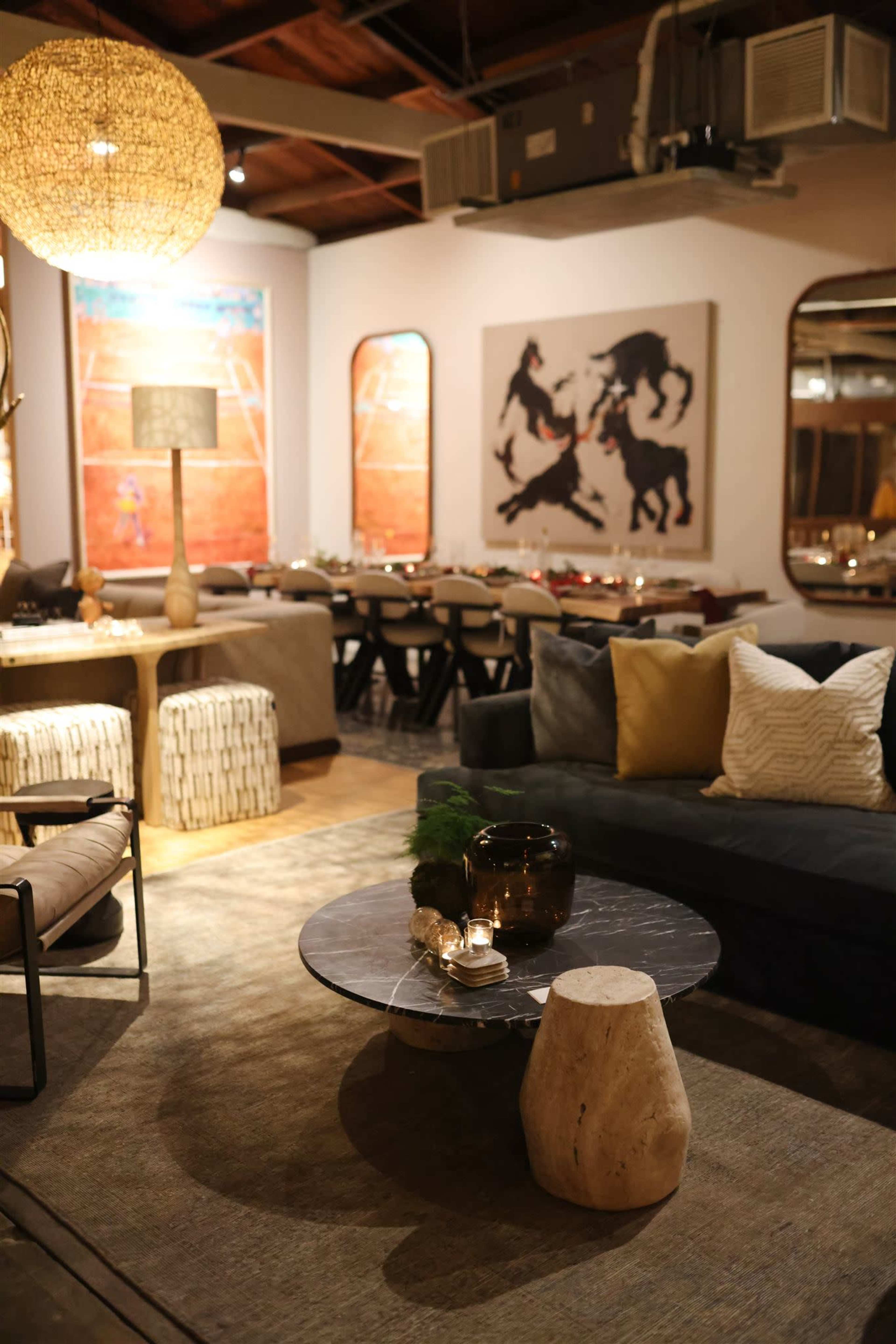 The image shows a modern restaurant interior with a mix of seating arrangements, artistic wall decor, and a central coffee table.