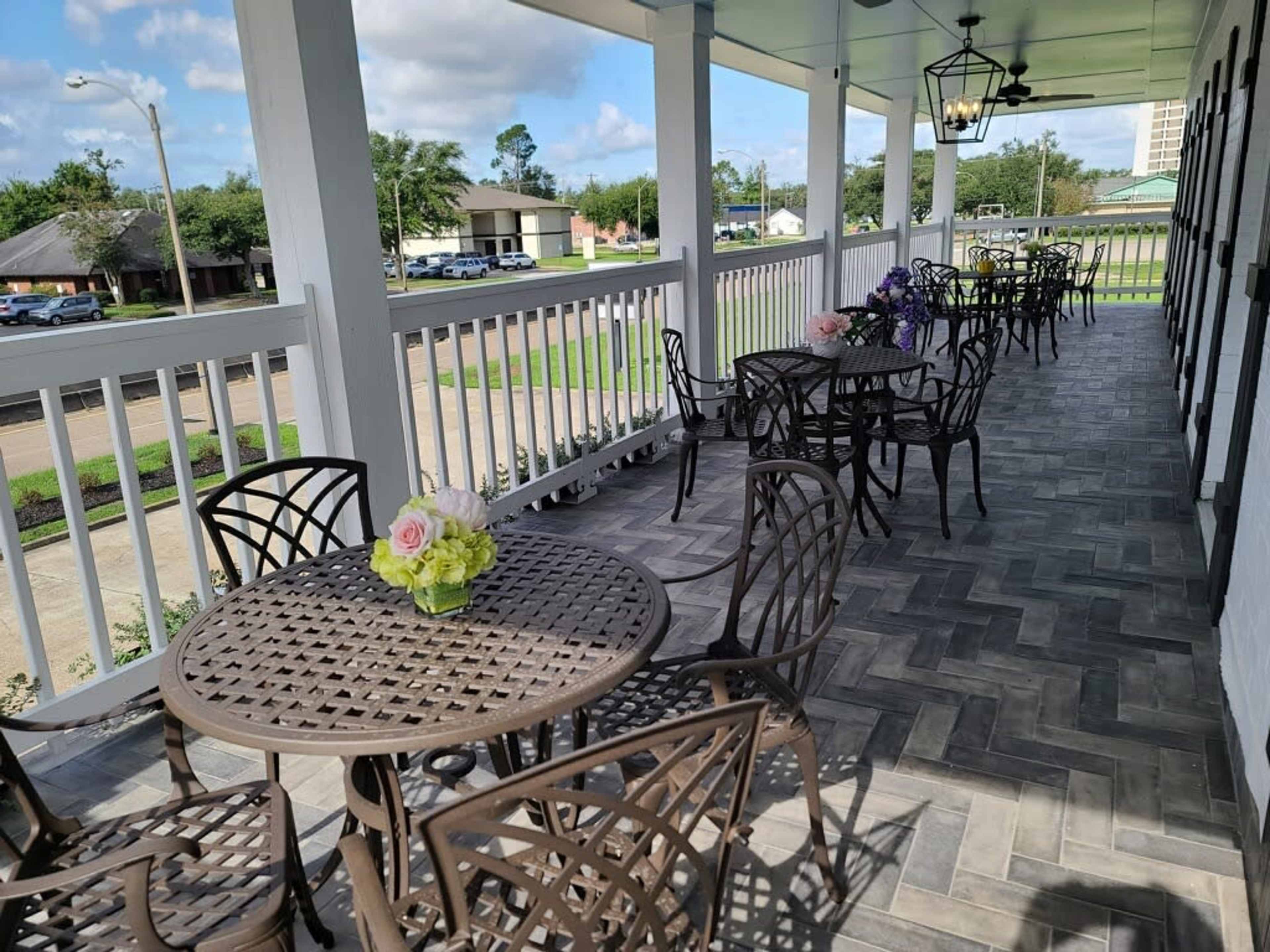A patio area with several round tables and chairs, decorated with a flower arrangement.