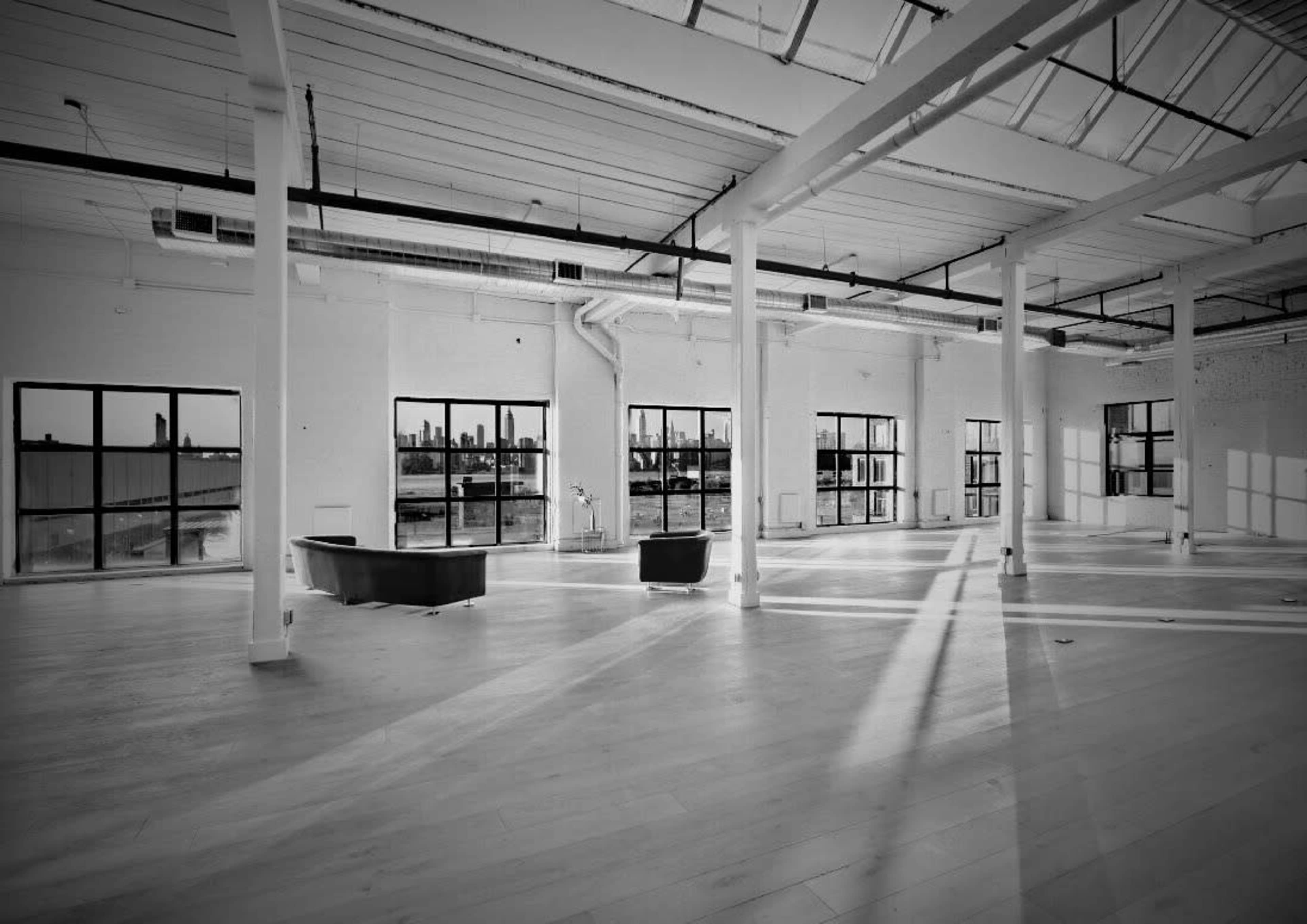 An empty, well-lit industrial space with large windows and a minimalist interior design.
