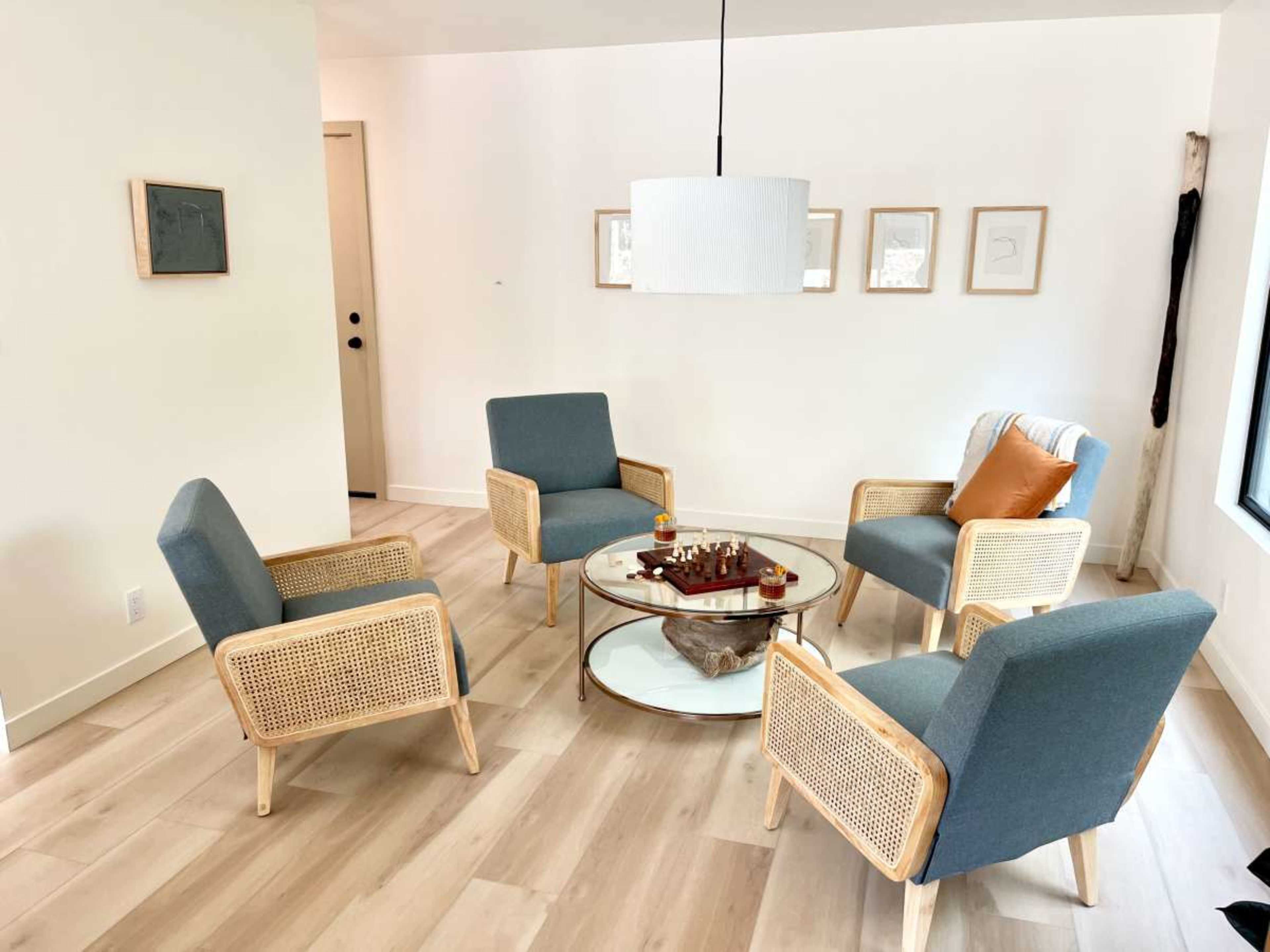 A modern seating area features four upholstered chairs arranged around a circular coffee table with a chess set on it.