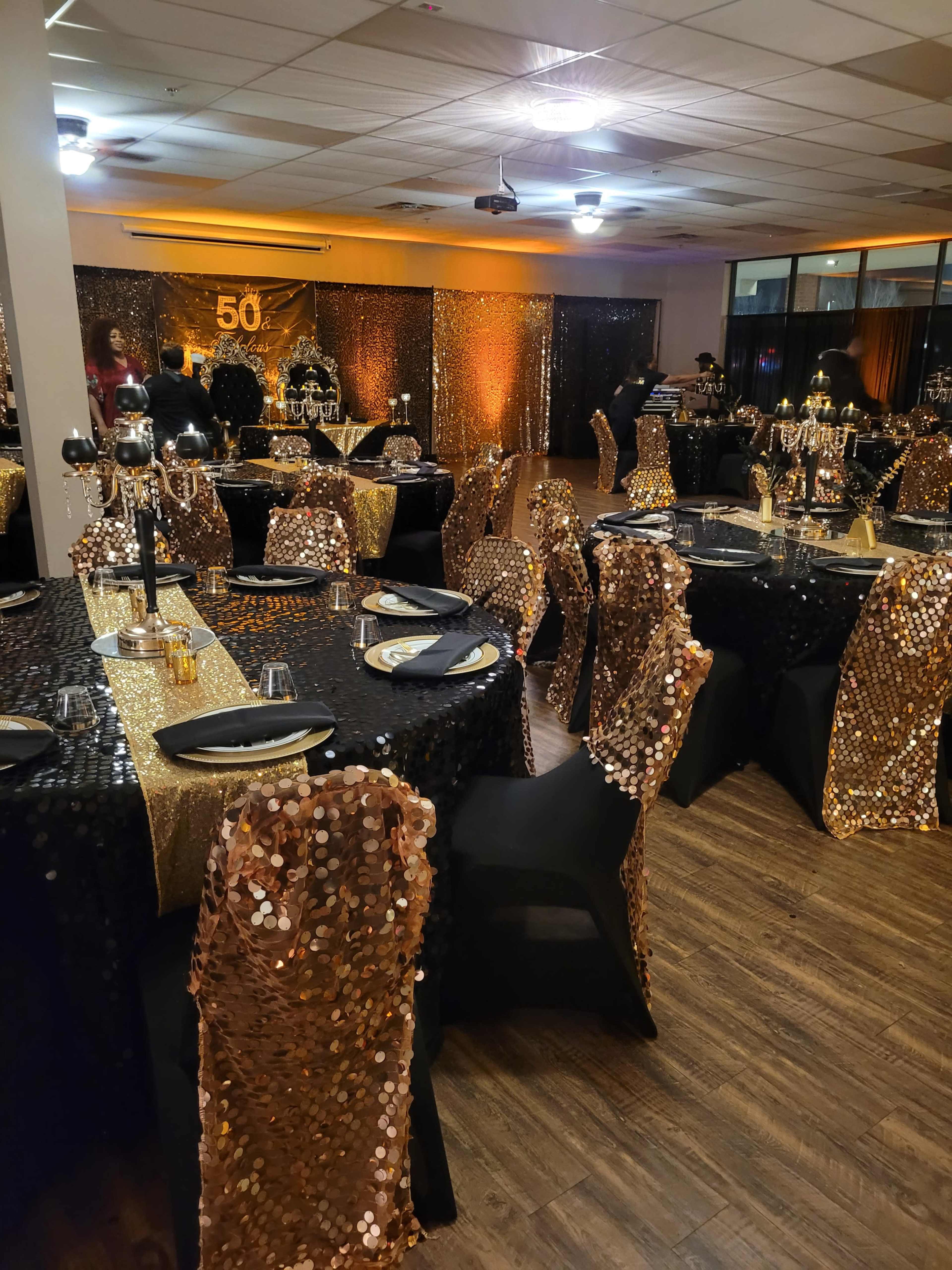 A banquet hall set for a 50th celebration, featuring tables covered in sequined tablecloths and chairs draped in sequined covers.