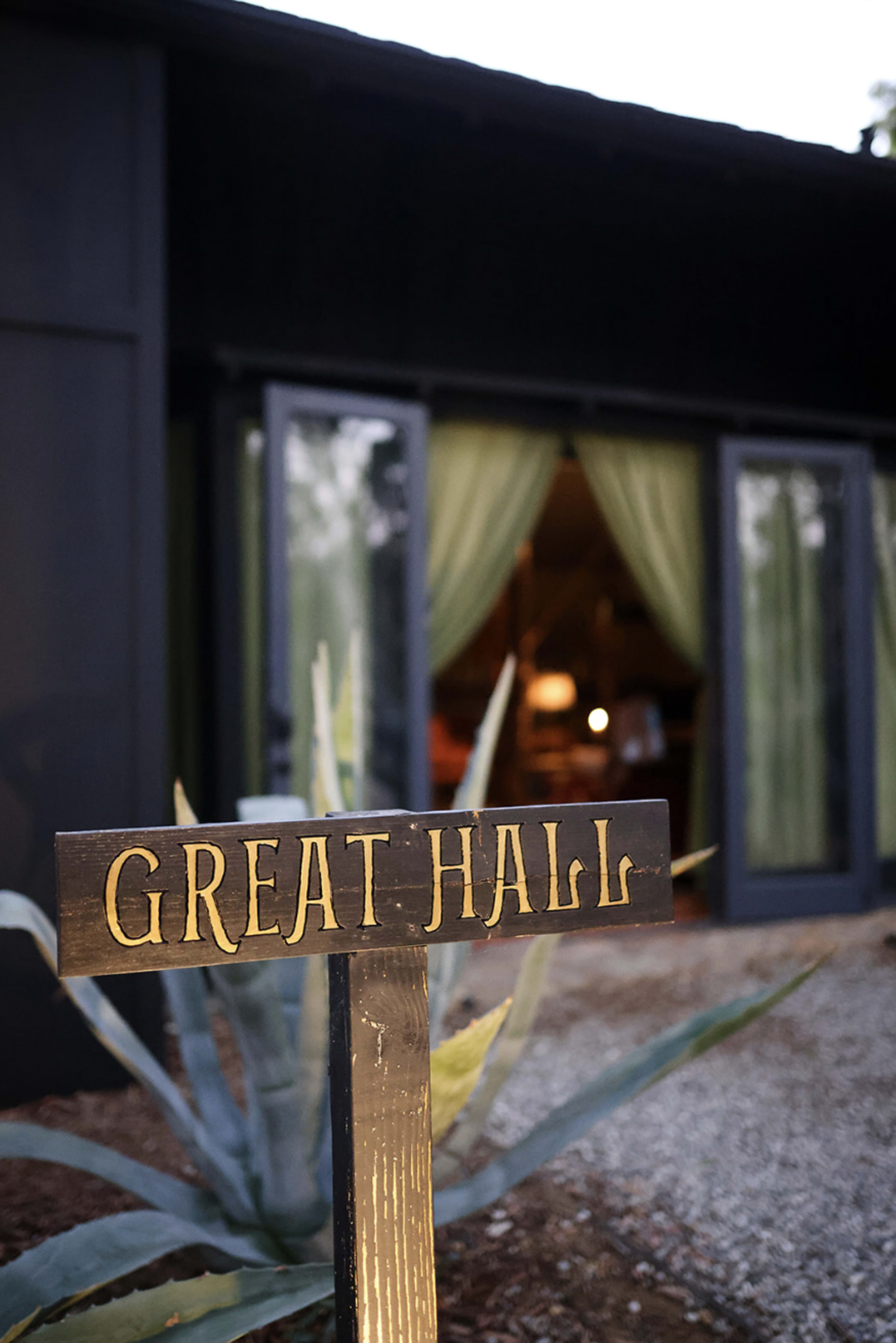 A sign reading "GREAT HALL" stands in front of a building with large windows and green curtains.