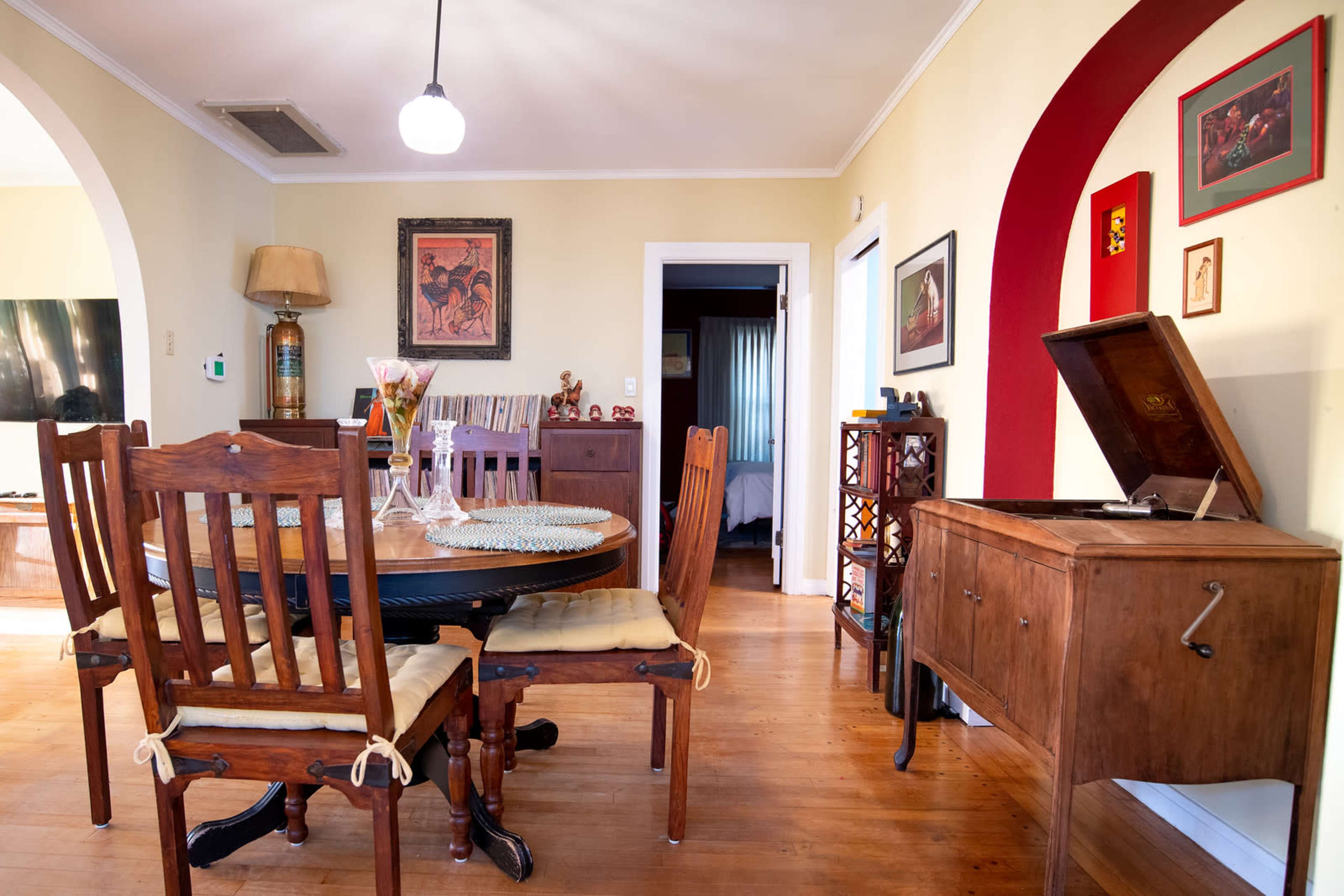A cozy dining area featuring a wooden table surrounded by chairs, a record player, and various framed artworks on the walls.