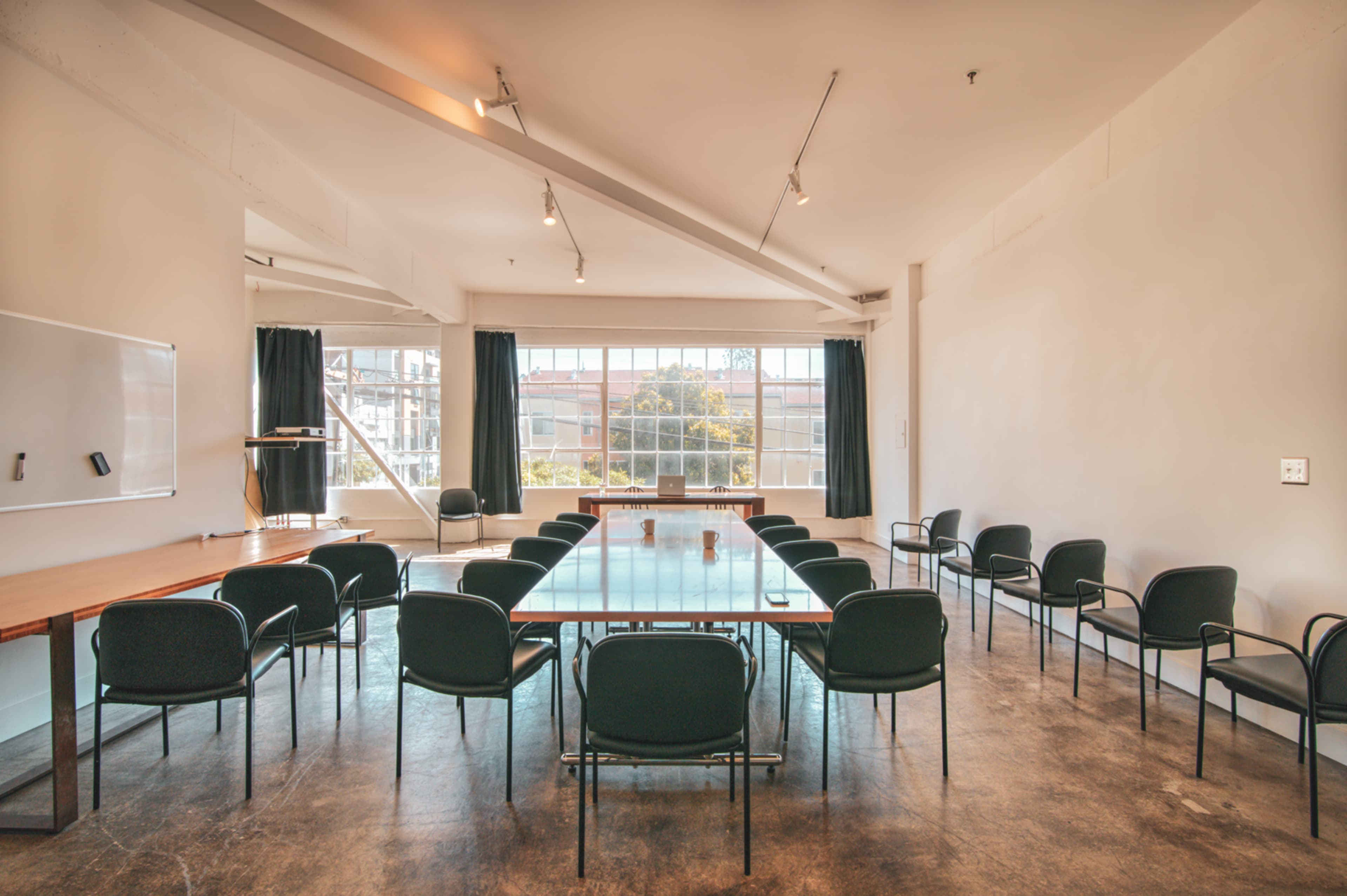 A large meeting room features a long table surrounded by chairs and a large window letting in natural light.