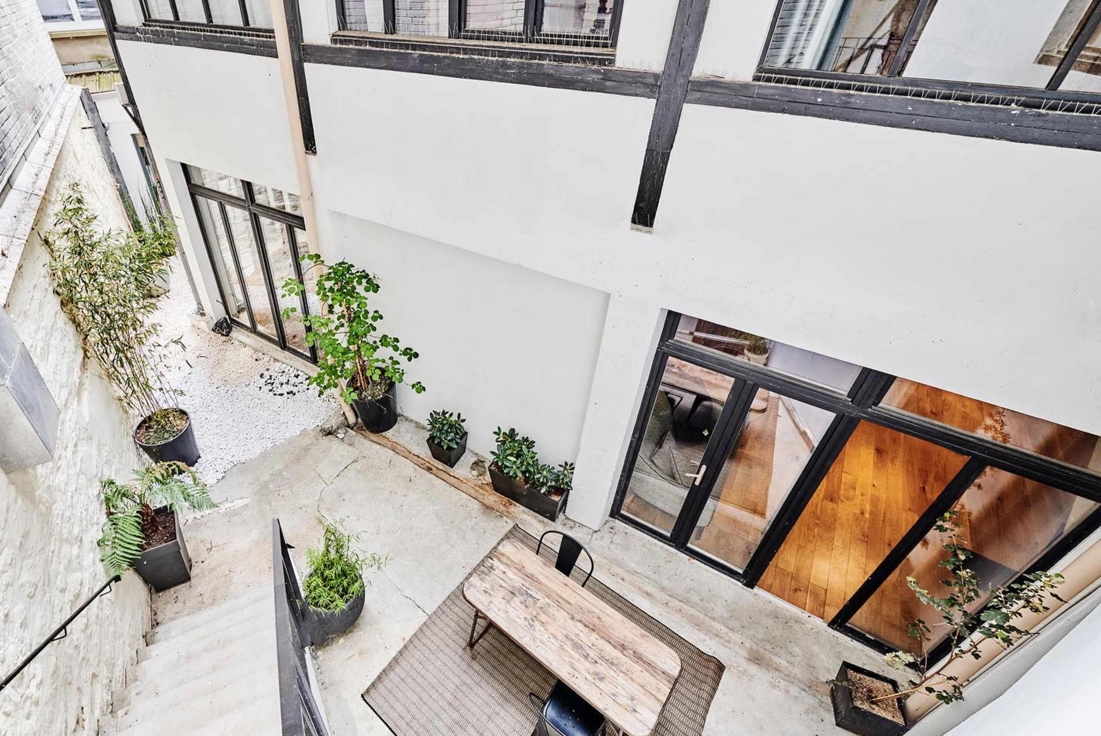 An aerial view of a modern courtyard with stone steps, potted plants, and a wooden table.