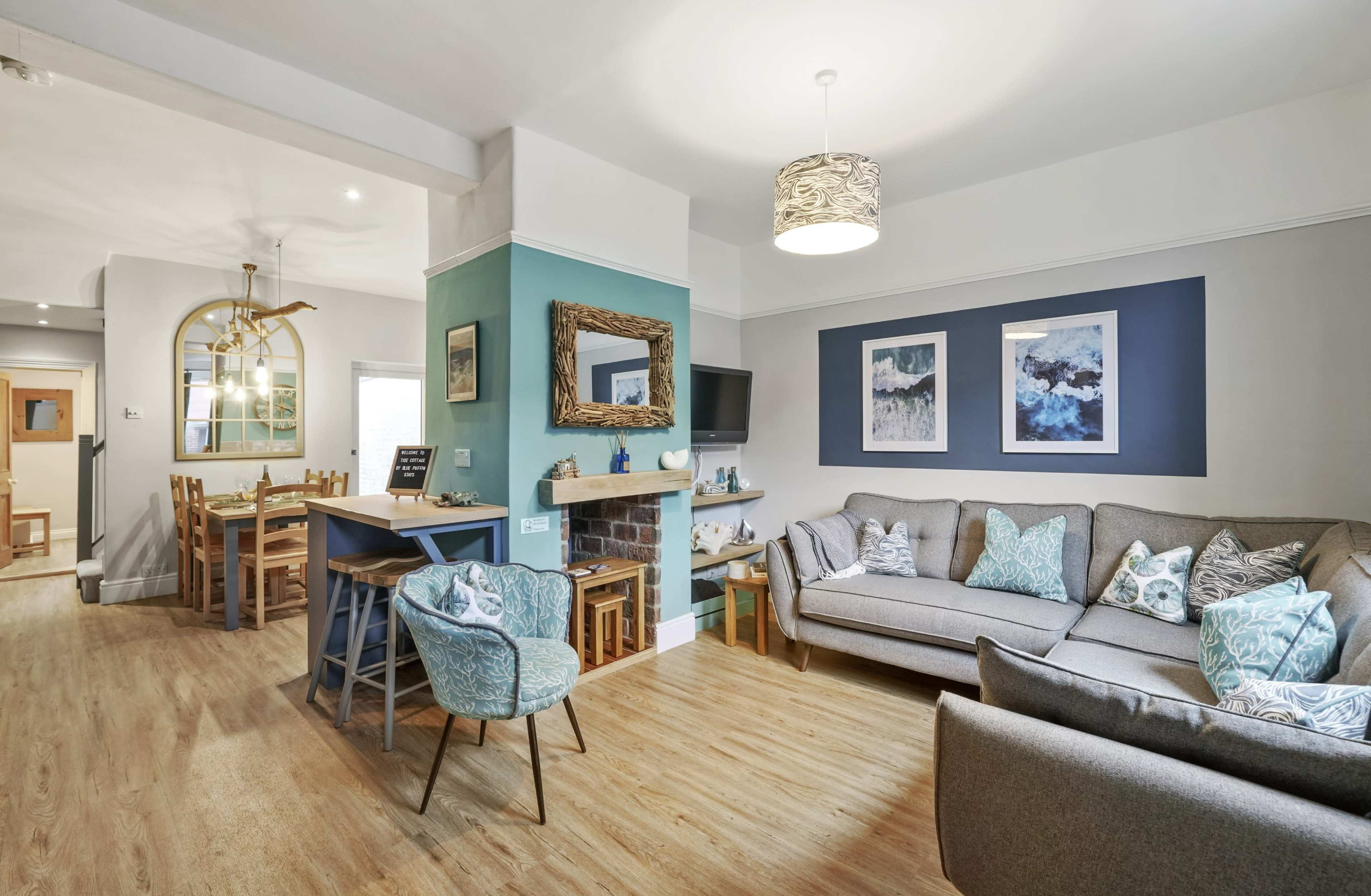 A cozy living space featuring a gray sofa, a dining area with a wooden table, and blue and green wall accents.