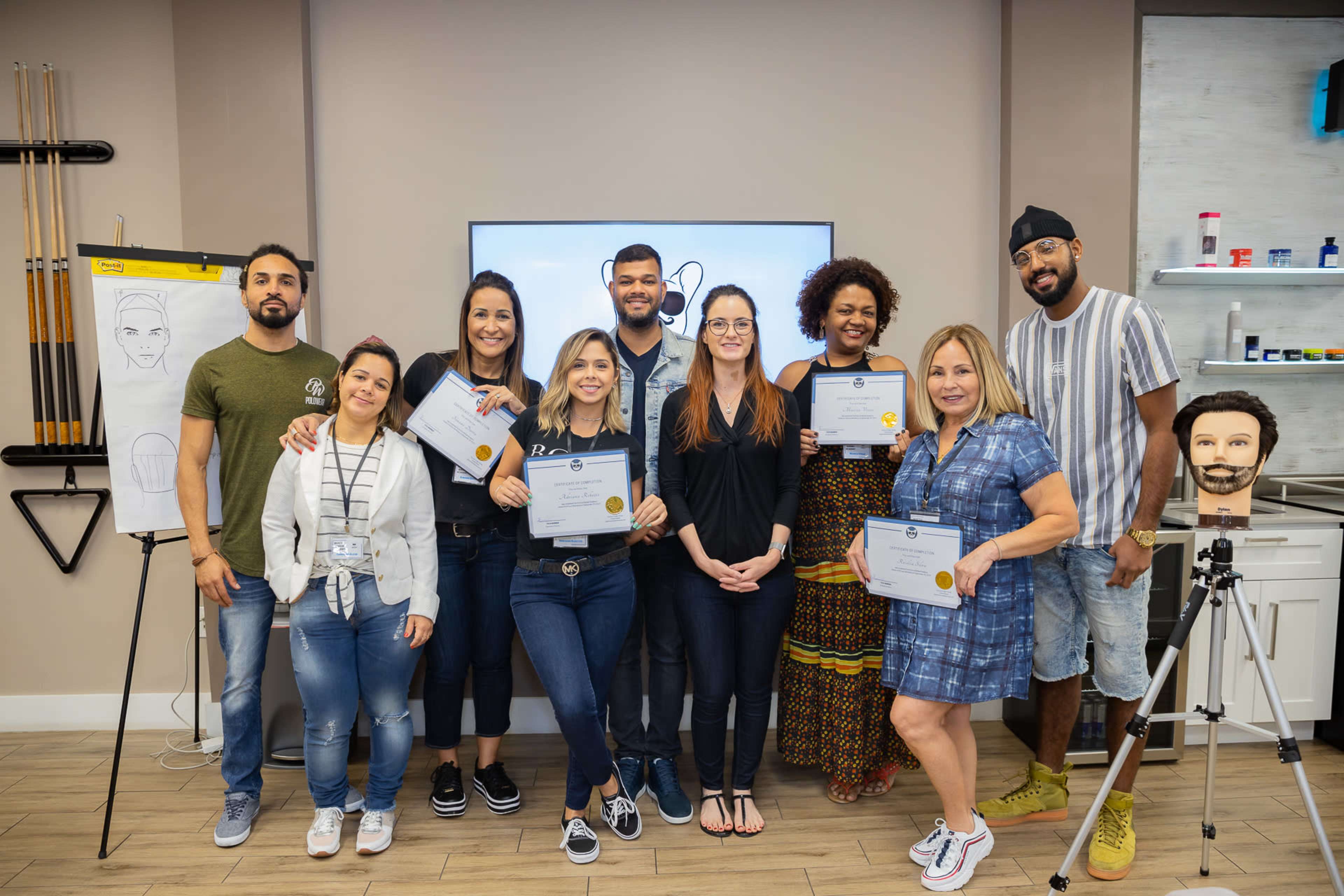 A group of eight individuals stands in front of a screen displaying a sketch, each holding a certificate.