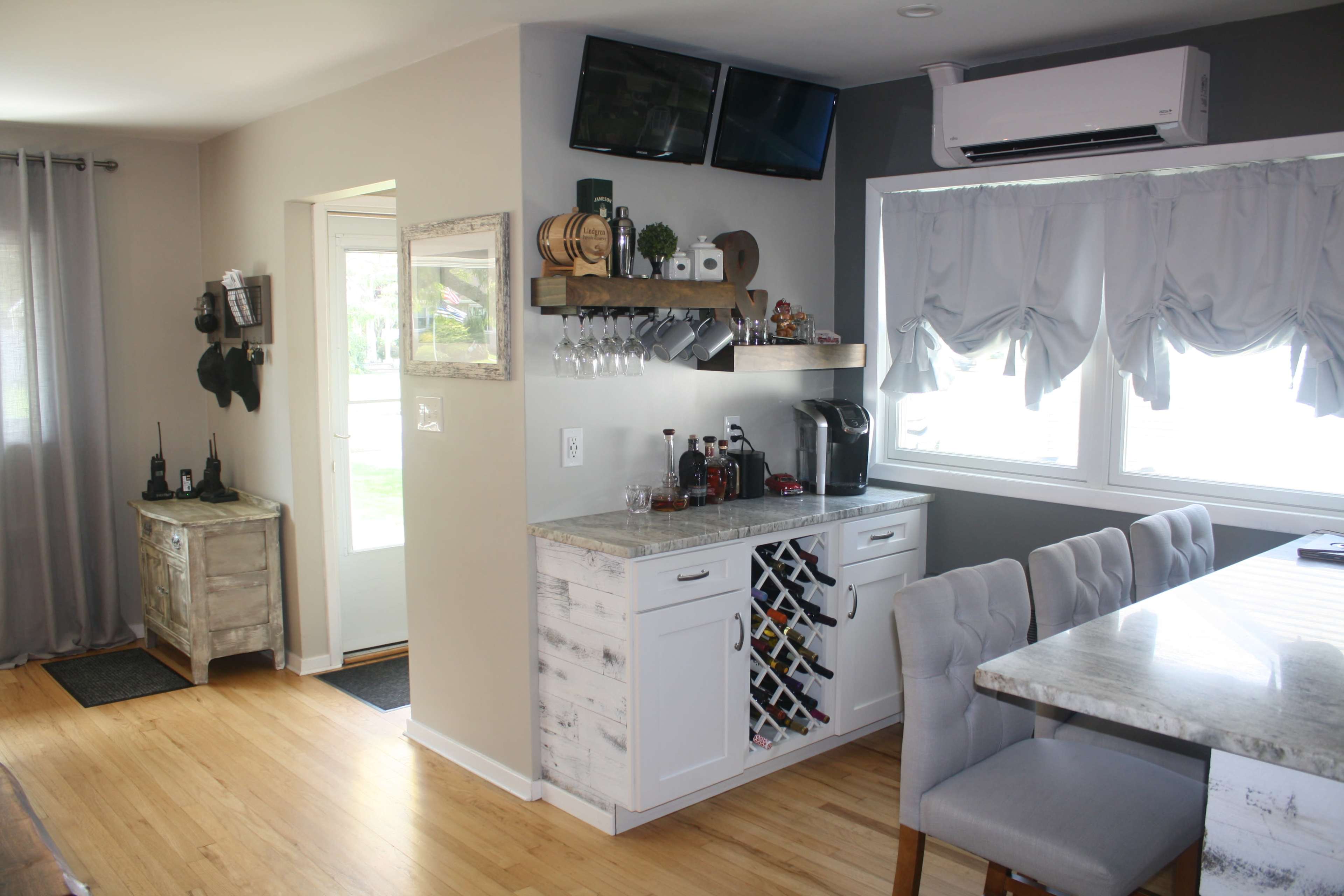 A modern kitchen features a wine rack, a coffee station, and an inviting dining area with plush chairs.