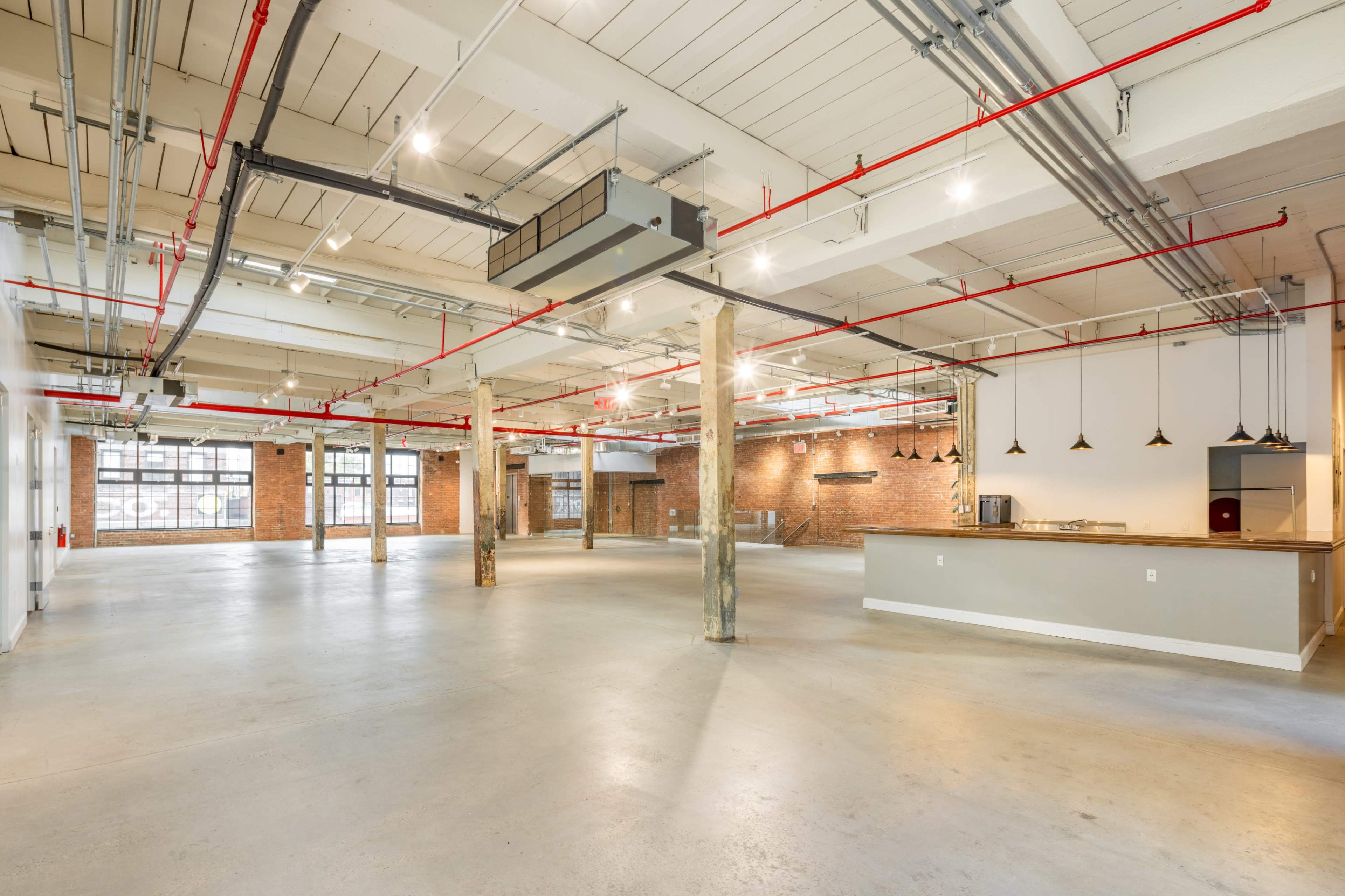 A spacious industrial-style interior with exposed brick walls, pendant lights, and concrete floors.