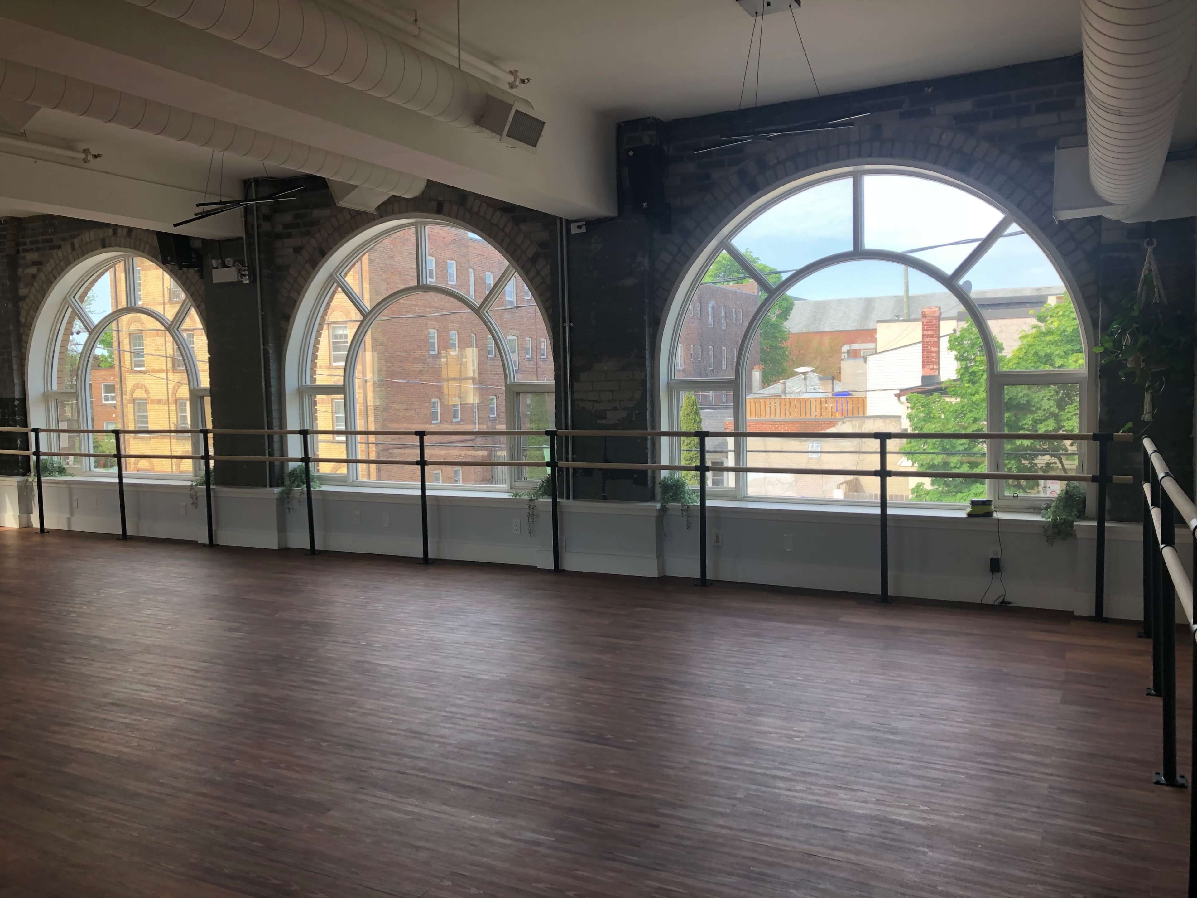 The image shows a spacious, well-lit interior with large arched windows overlooking a street lined with buildings.