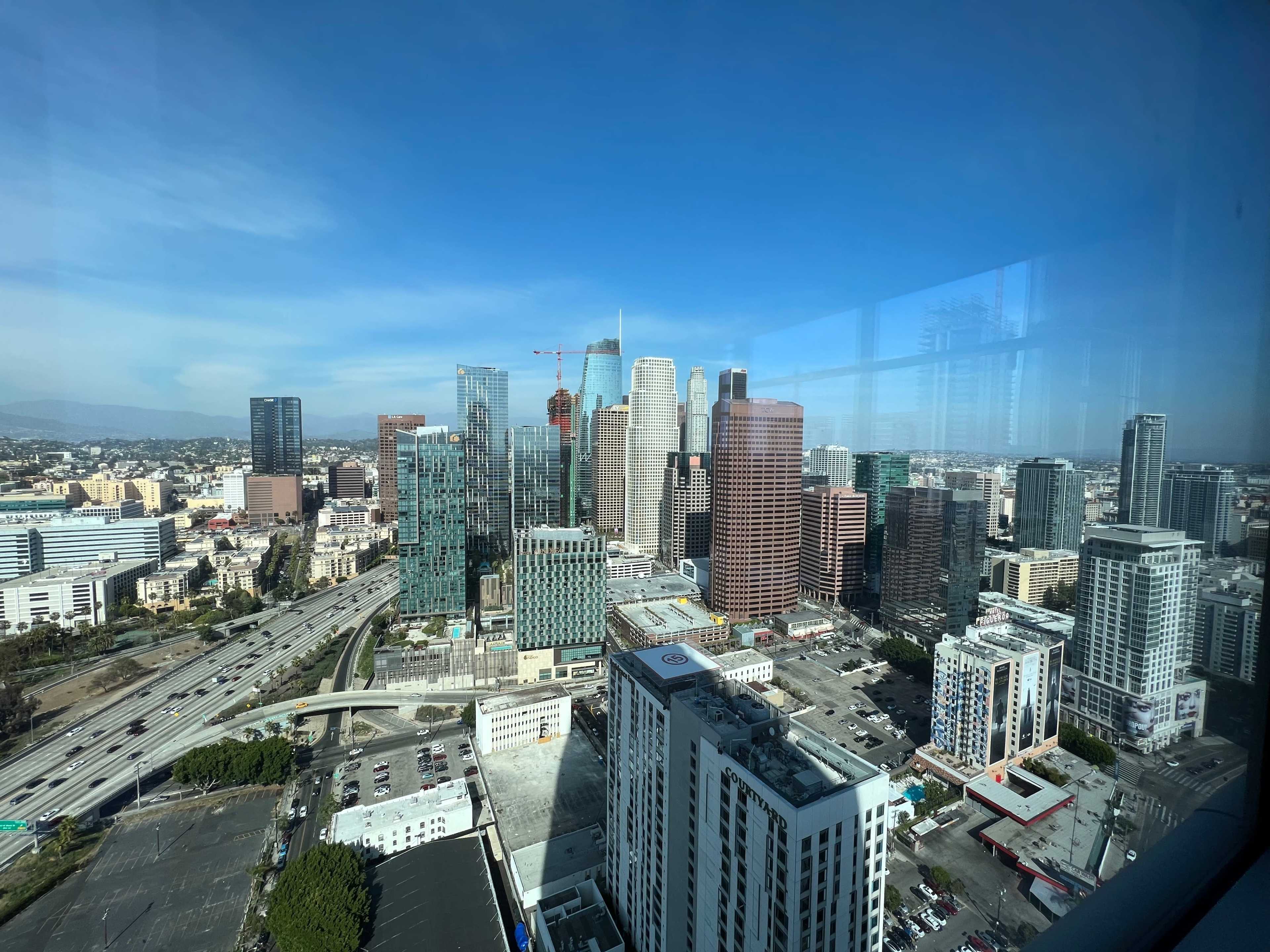 A panoramic view of downtown Los Angeles, featuring a mix of skyscrapers and a clear blue sky.