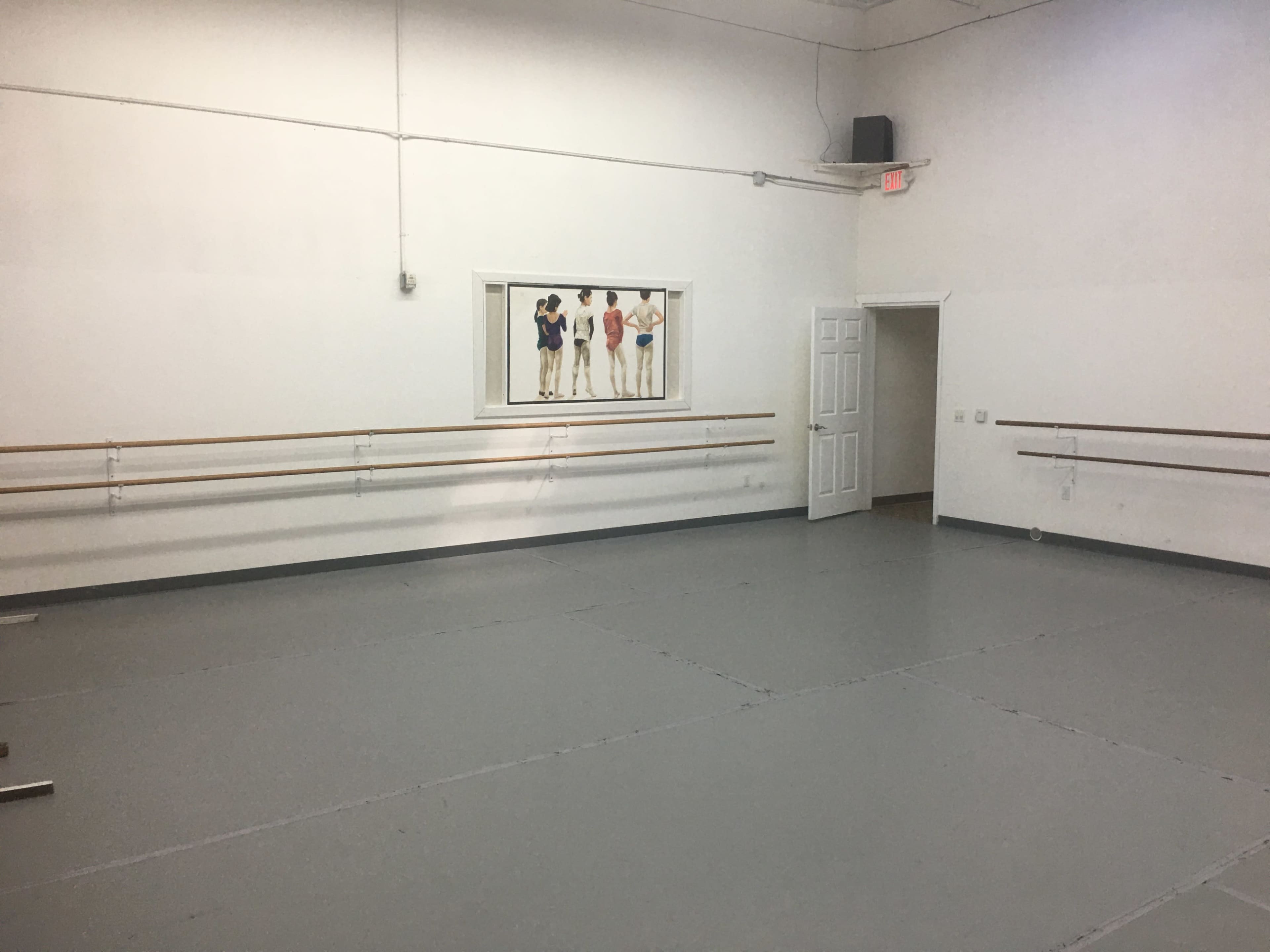 A spacious ballet studio features wooden barre along the walls and a mural of dancers in the center.