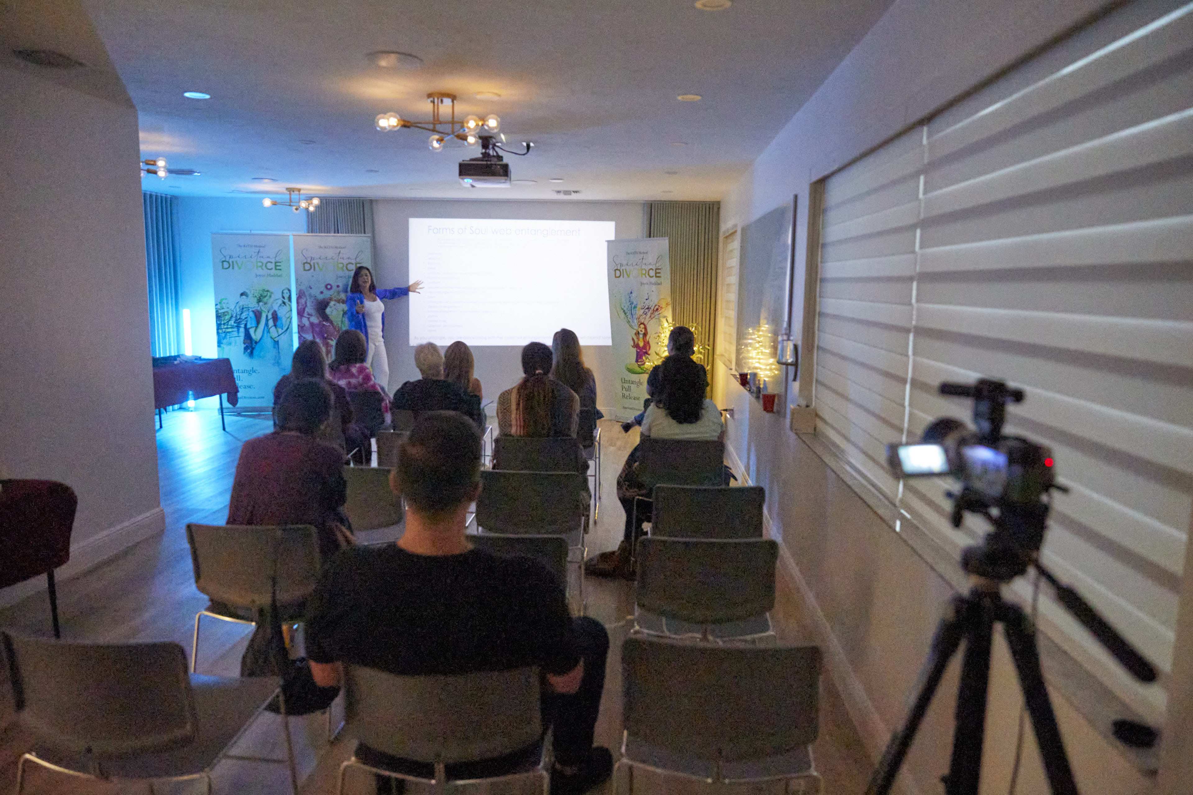 A presenter stands in front of a projected slide while an audience listens during a workshop about divorce.