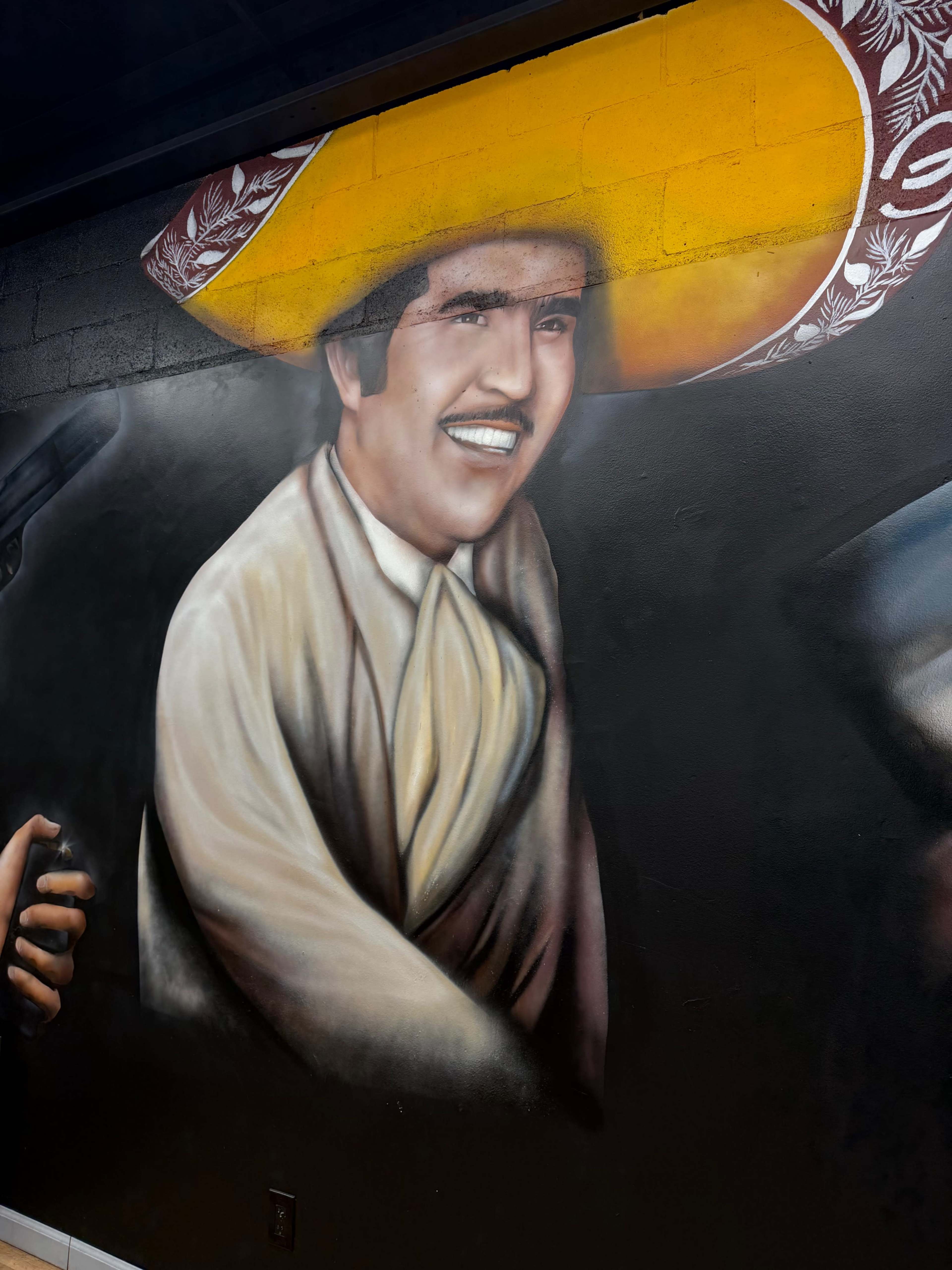 The image features a colorful mural of a man wearing a large sombrero, painted on a wall.