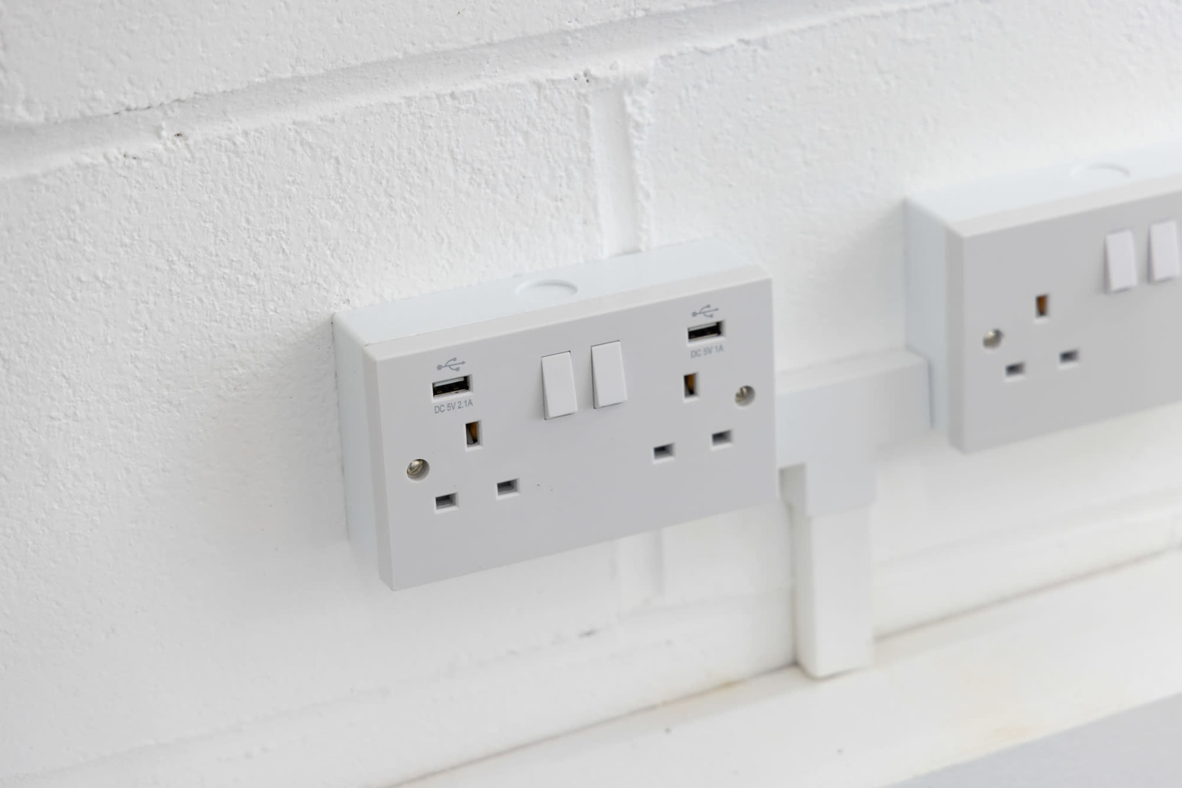 A white electrical outlet panel mounted on a white wall, featuring multiple power sockets and USB ports.