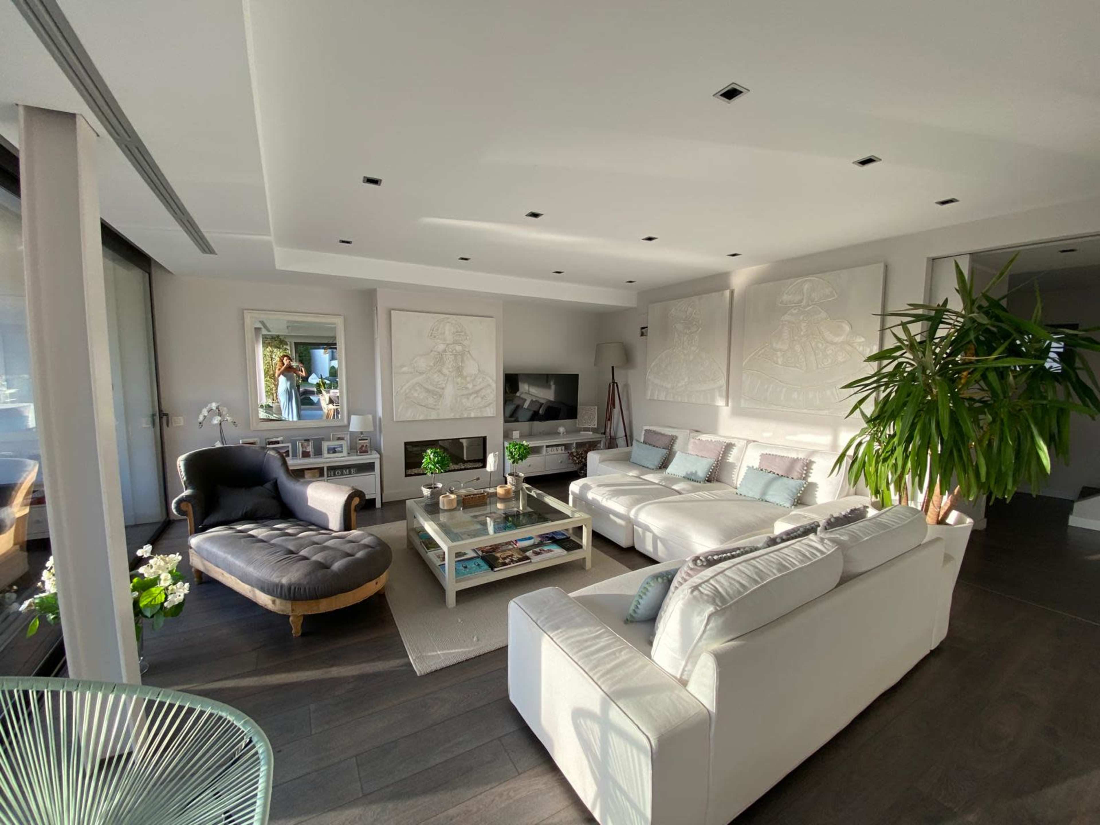 The image shows a bright, modern living room with a large sectional sofa, a coffee table, and decorative wall art.